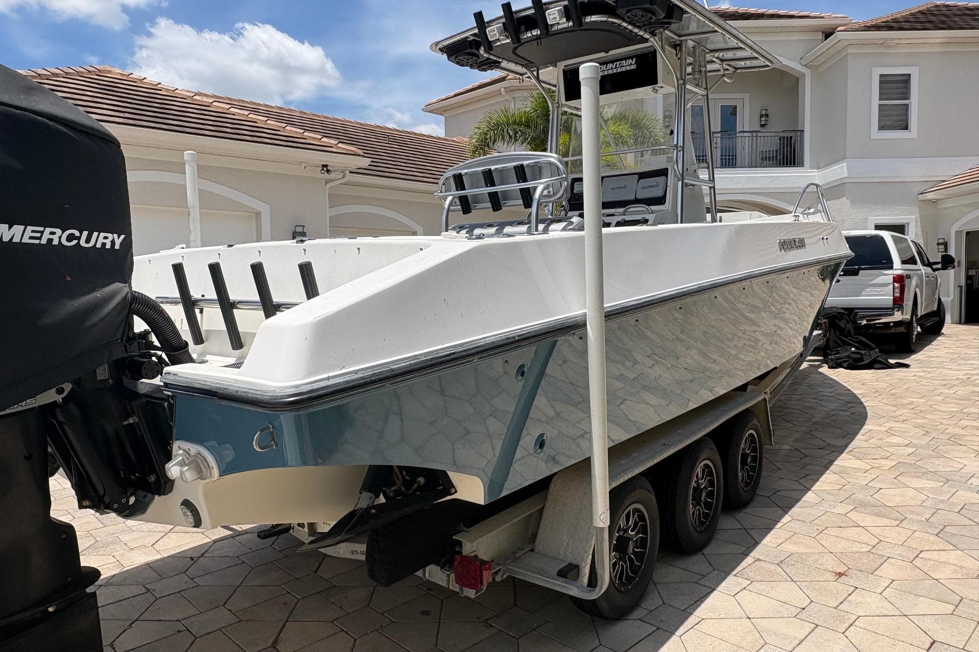 2001 Fountain 31 Center Console boat on trailer in driveway, with Mercury engine.
