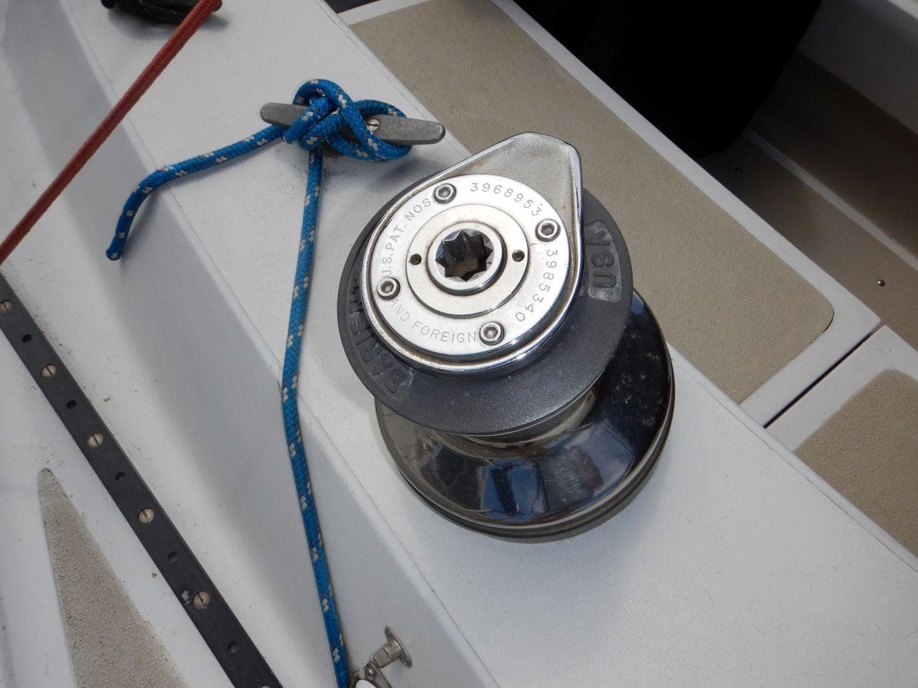 Winch on 1978 Islander Sloop sailboat with blue rope tied securely.