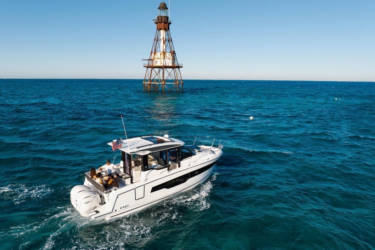 2025 Jeanneau NC 895 Series 2 cruising near a lighthouse on open blue waters.