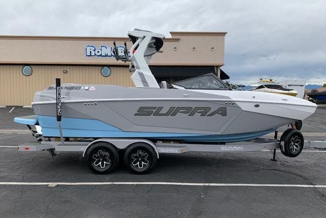 2026 Supra SA 450 boat on trailer, parked outside a building.