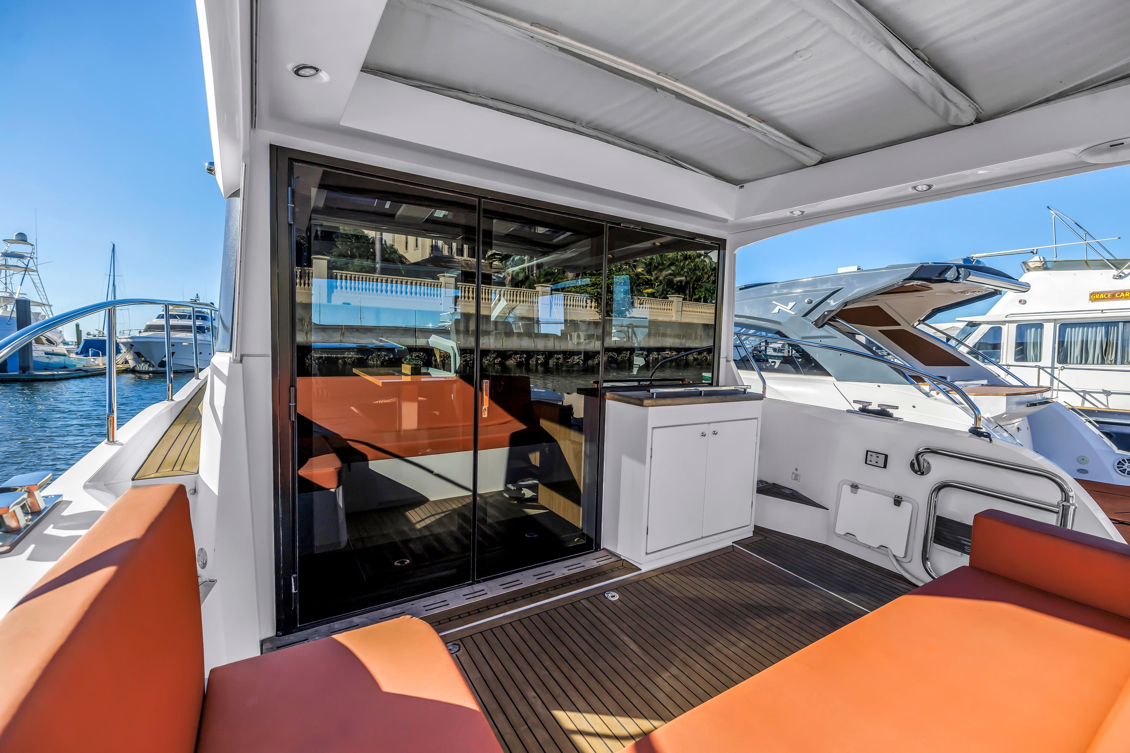 2020 Sealine C390 yacht with spacious deck, orange seating, and modern design in marina setting.