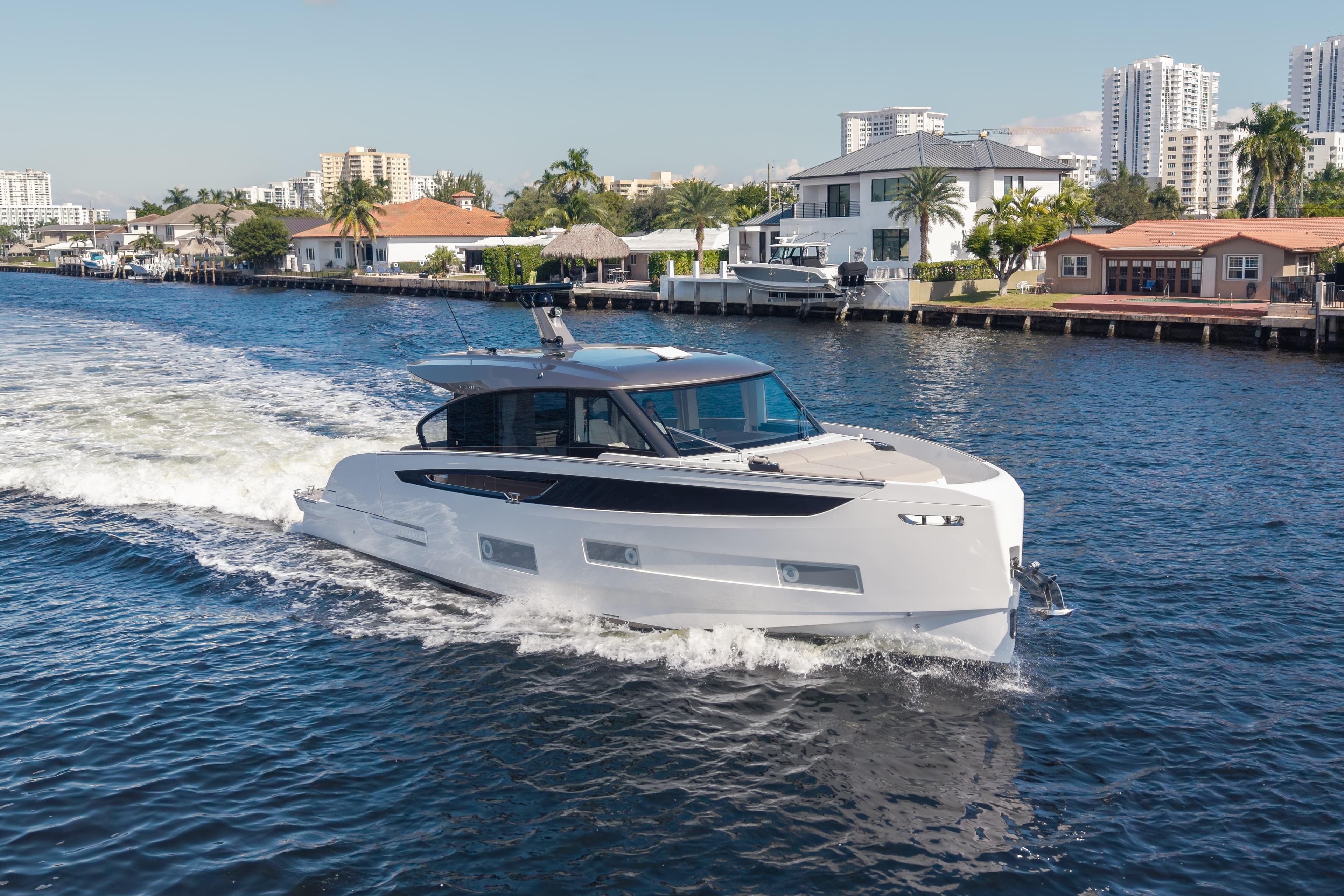 2025 Azimut Seadeck 6 yacht cruising on a scenic waterway near luxury homes.