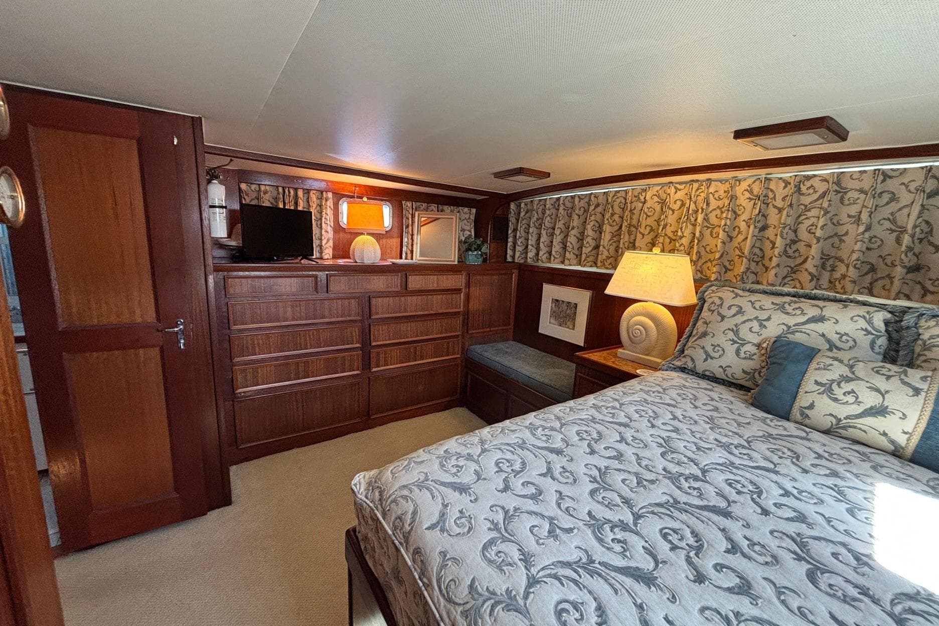 Interior of 1979 Hatteras 53 Motor Yacht with elegant wood furnishings and patterned bedding.