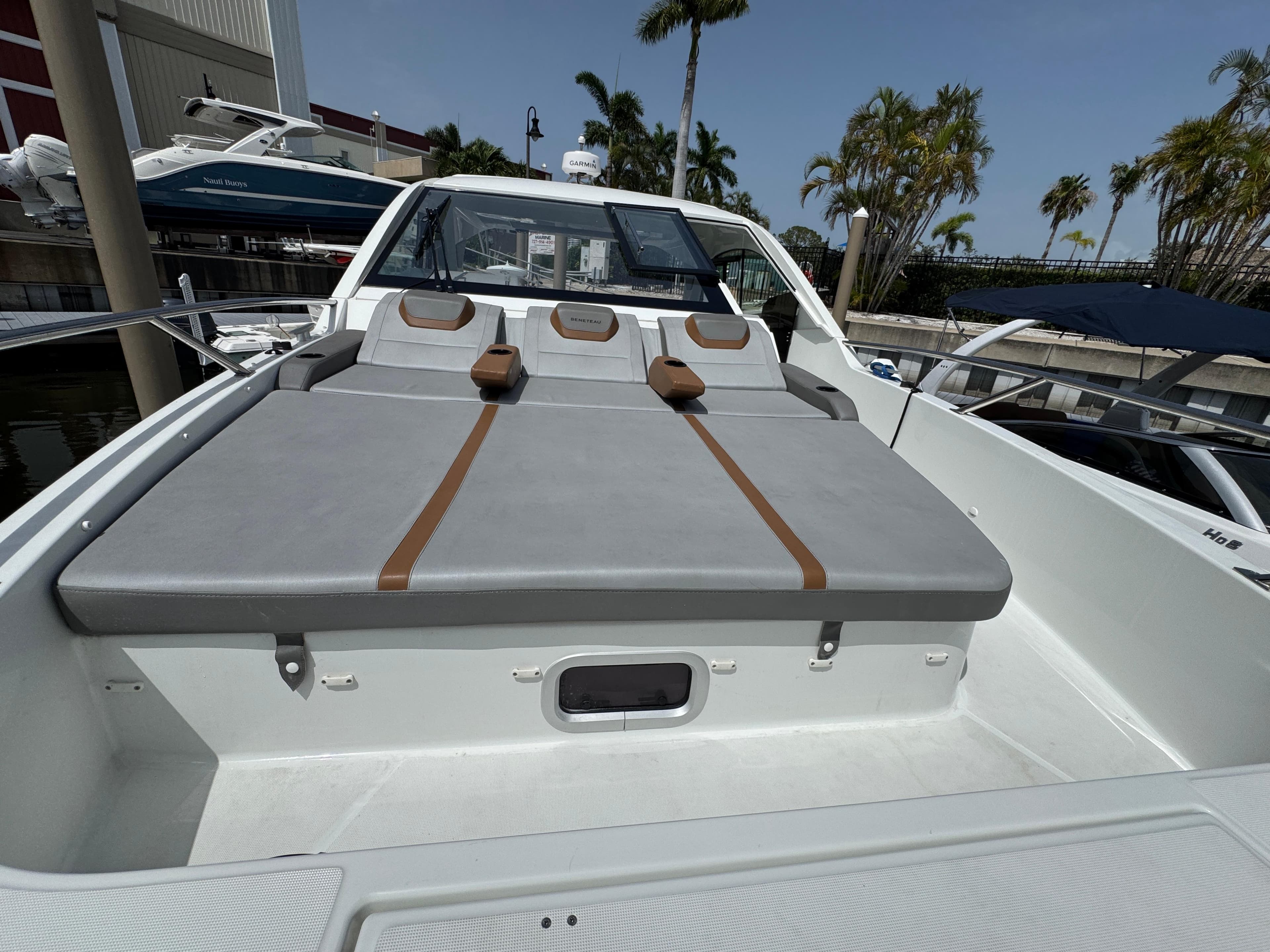 2022 Beneteau Gran Turismo 32 yacht with spacious sunbathing area, docked near palm trees.