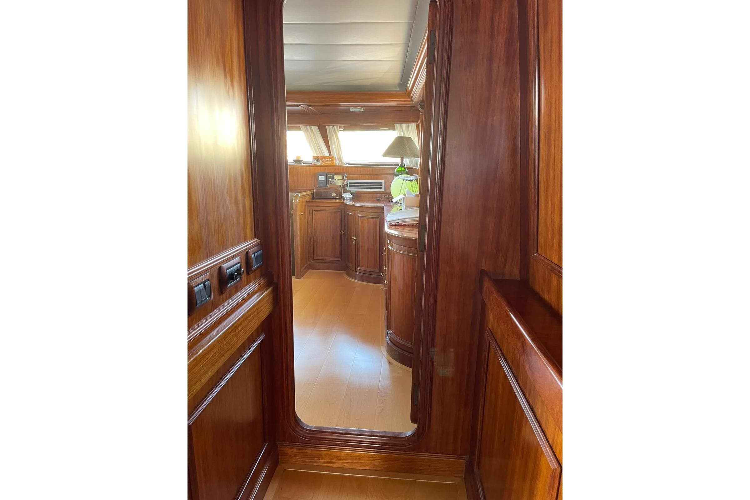 Luxurious wooden interior of 1985 Astondoa 24 yacht, featuring elegant cabinetry and mirror.