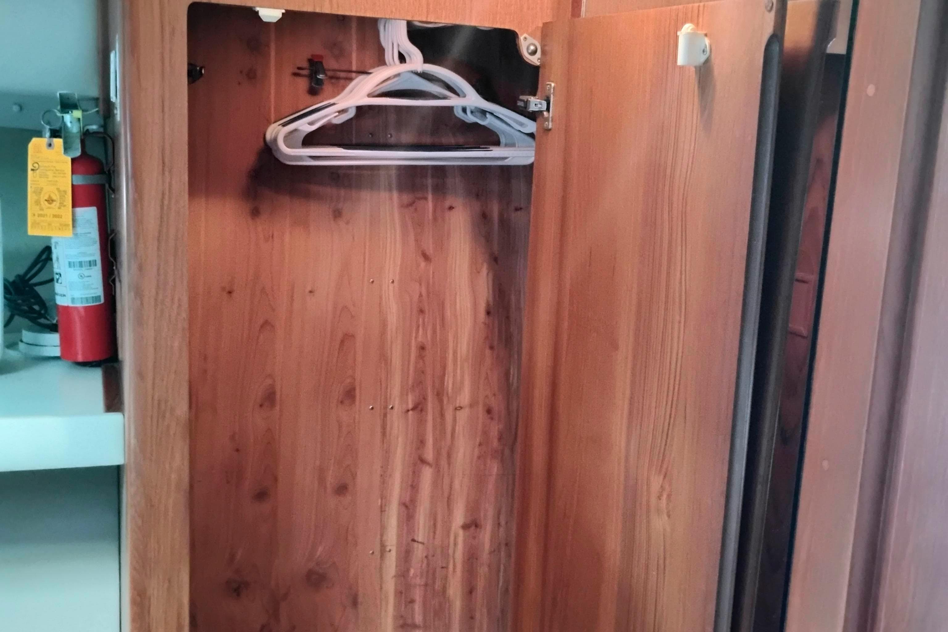 Wooden closet interior on 1991 Californian 52 Cockpit Motor Yacht with hangers and fire extinguisher.