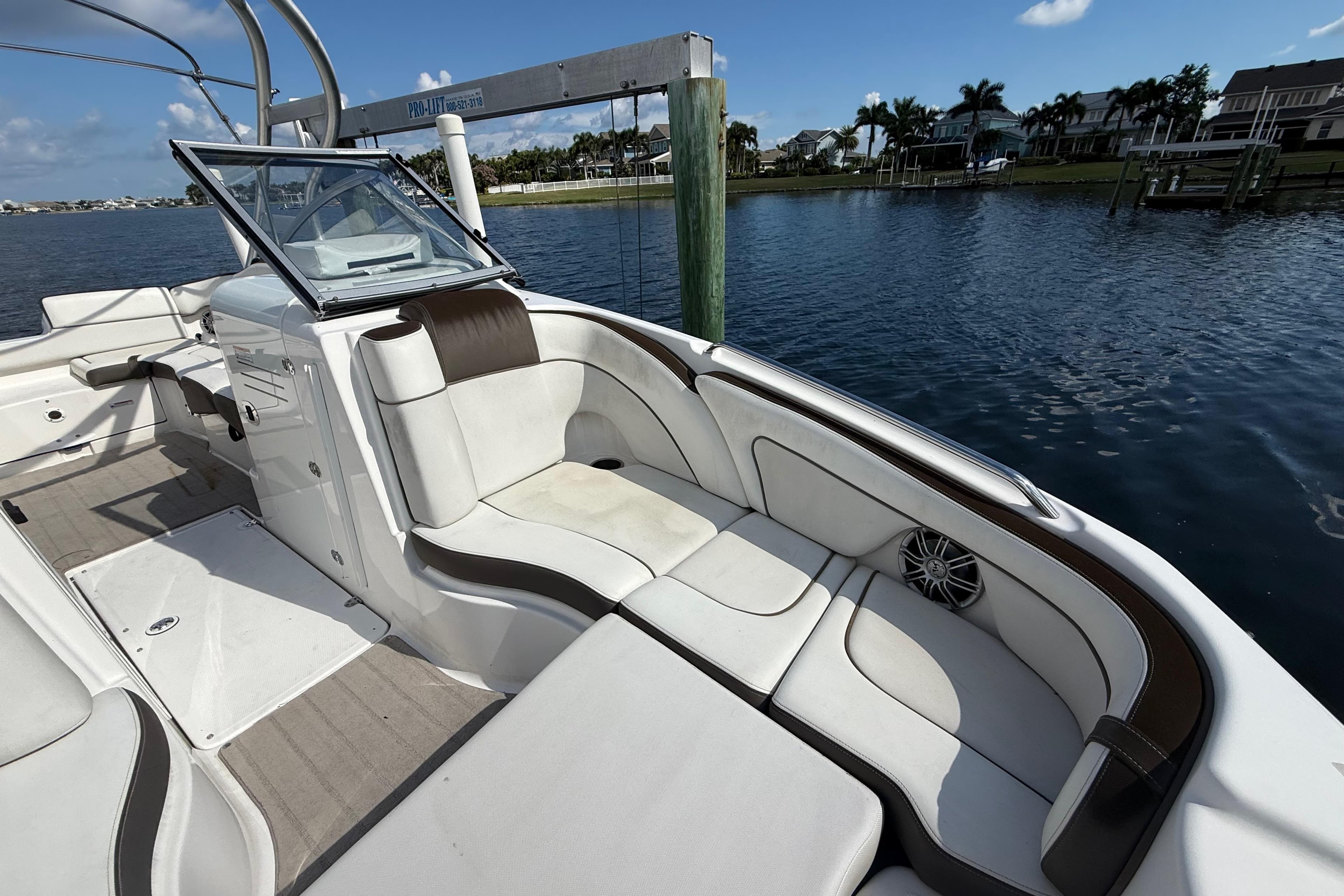 2014 Yamaha Boats 242 Limited S interior with white seating, docked by calm waters.