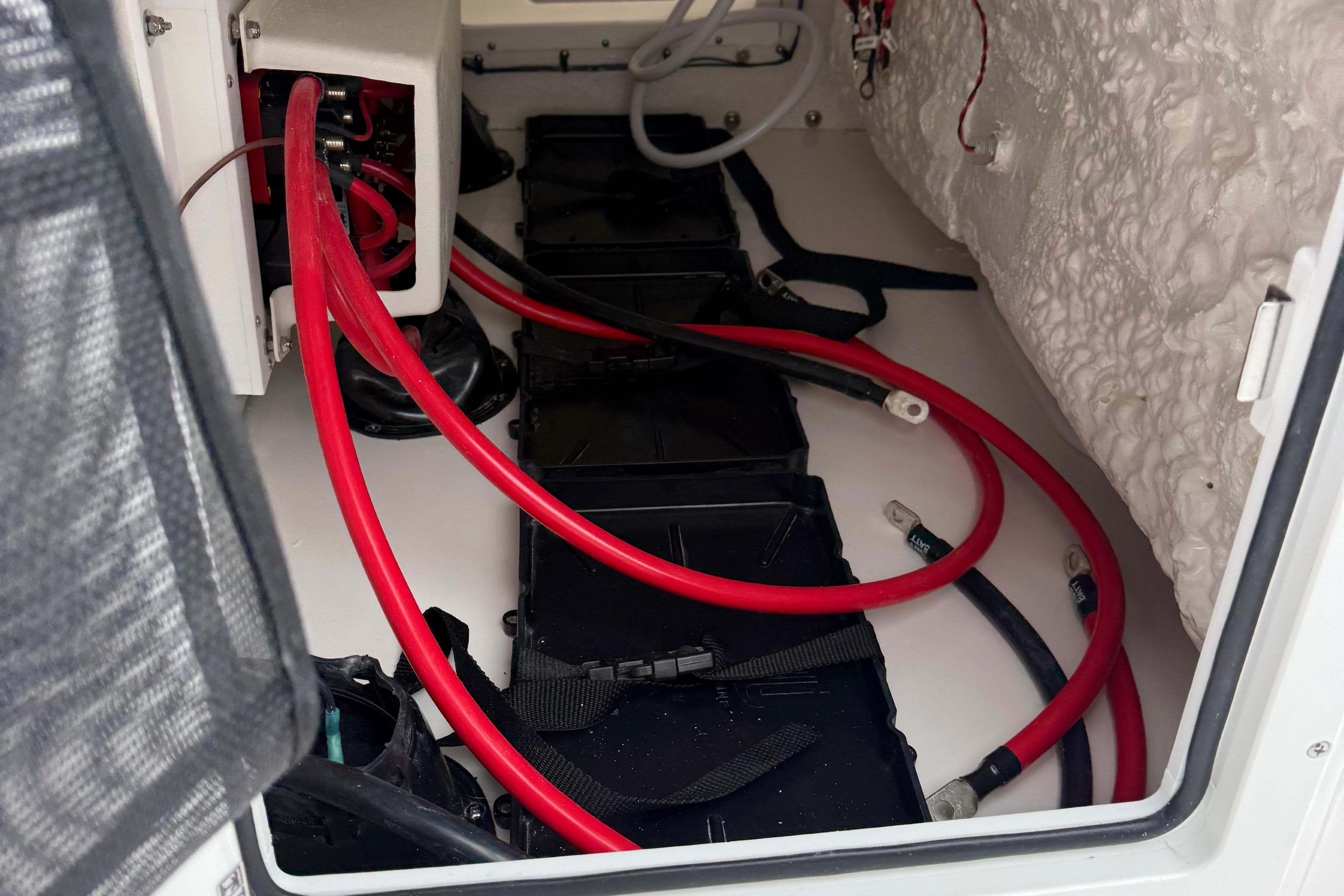 Battery compartment of 2026 Tidewater 282 CC Adventure boat with red cables.