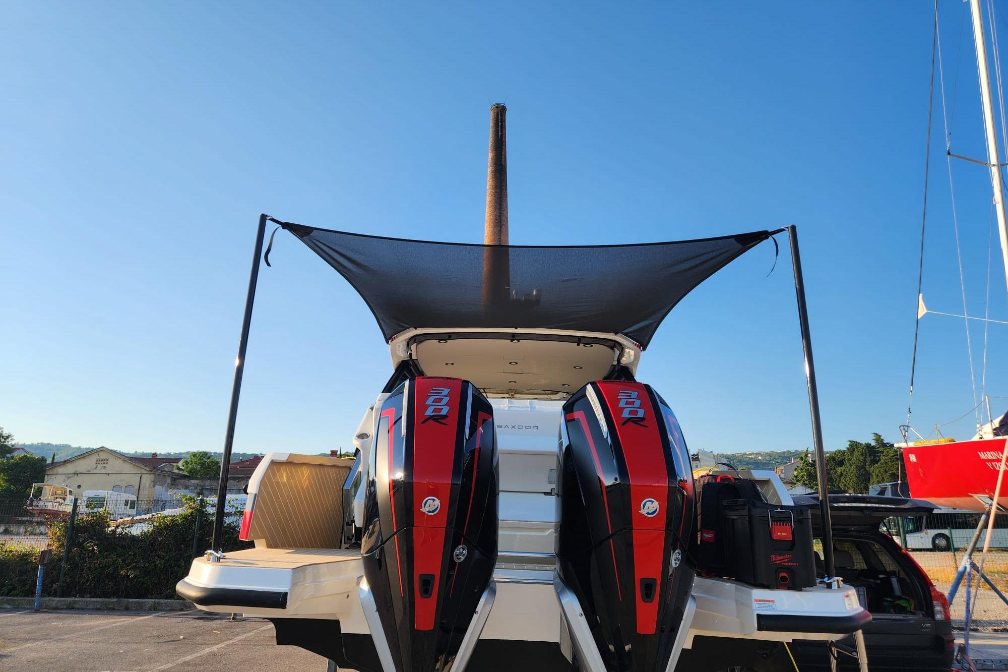 2025 Saxdor 320 GTO boat with dual outboard engines, docked under a clear blue sky.