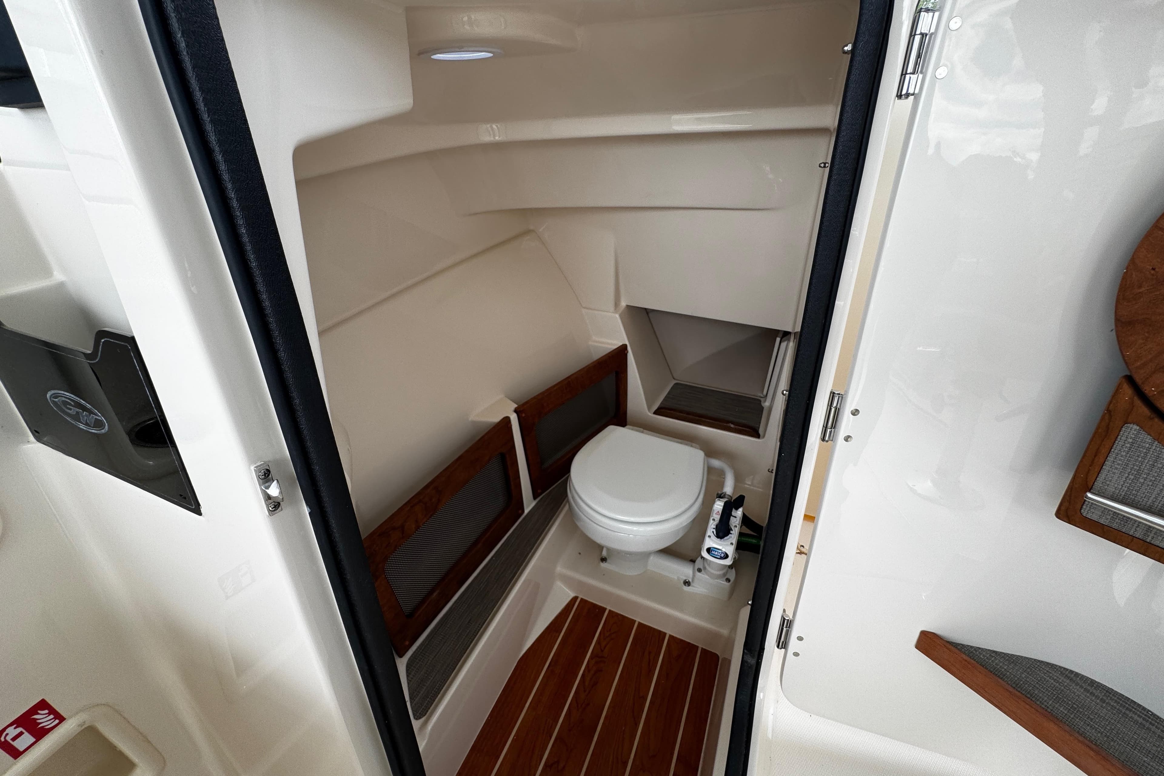 2026 Grady-White Freedom 235 boat interior with compact marine toilet and wooden accents.