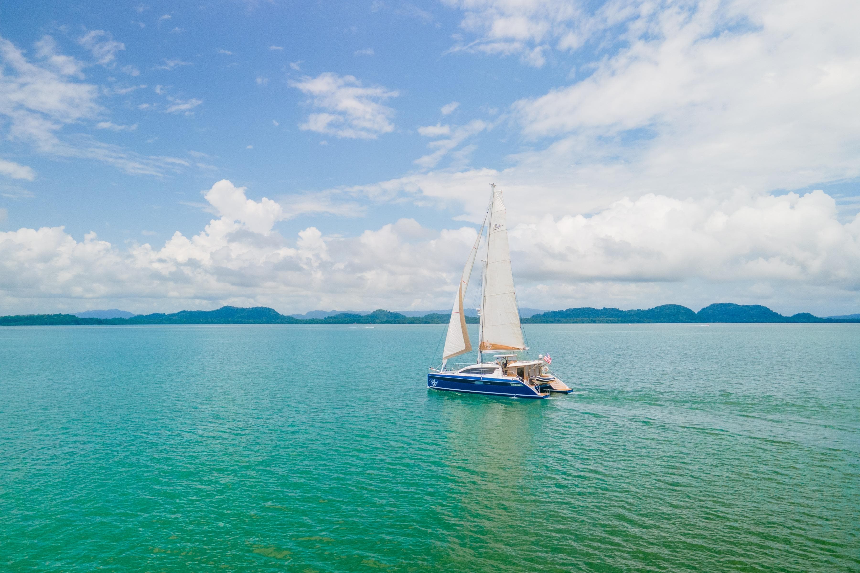 Sailing catamaran Privilege 510, 2023 model, cruising on turquoise waters under a clear sky.