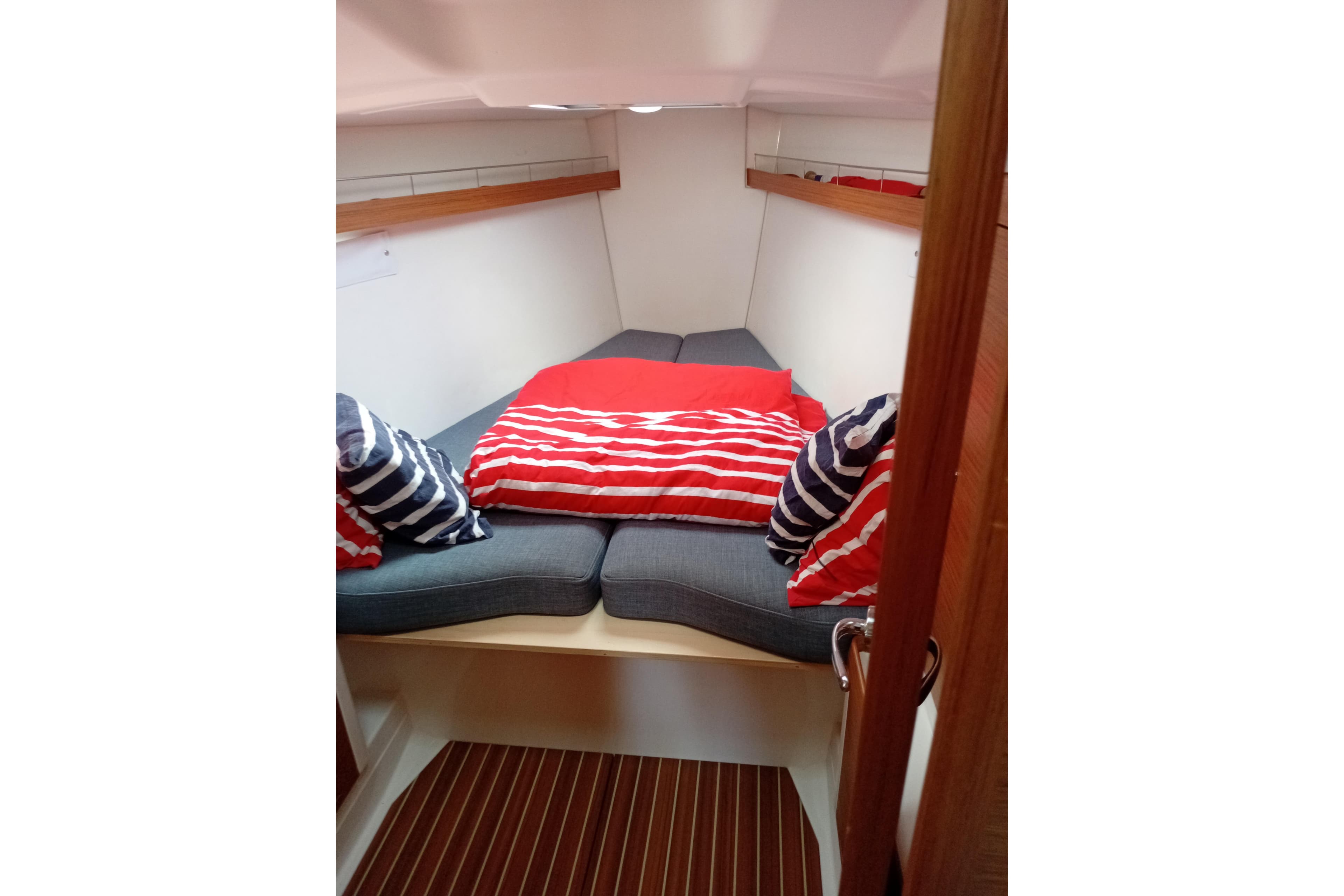 Cozy cabin interior of 2016 X-Yachts Xp 38 with striped bedding and cushions.