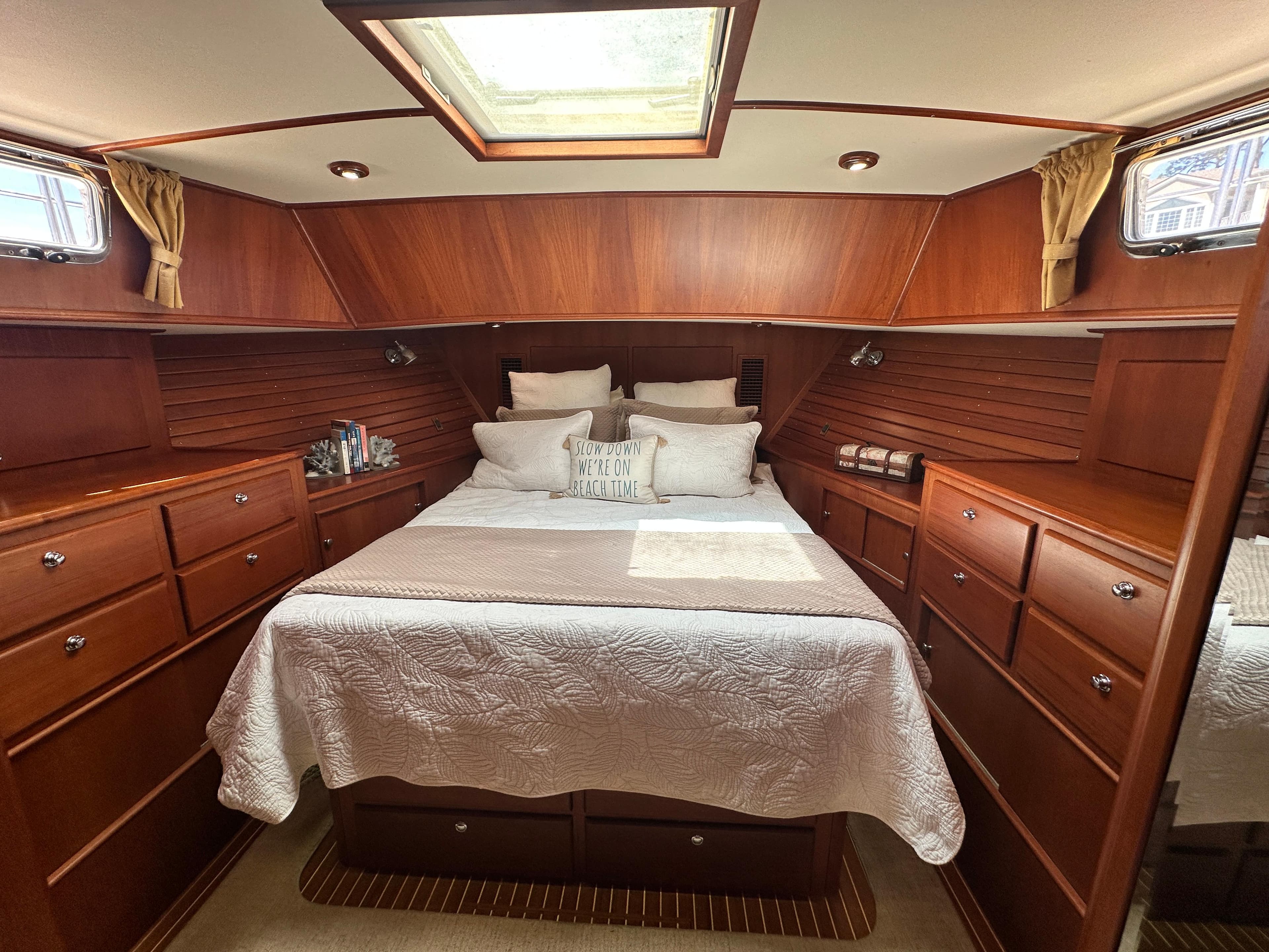 Luxurious 2004 Grand Banks 49 Eastbay HX cabin with elegant wood finish and cozy bedding.