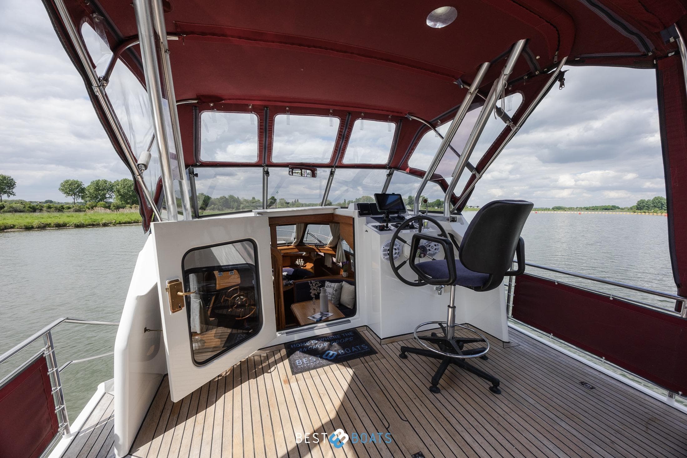 Linssen 37 SE 1992 yacht cockpit with red canopy, steering wheel, and river view.