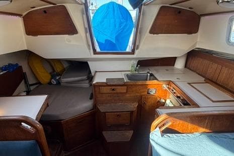 1985 Sabre 32 sailboat interior with wood cabinetry, compact kitchen, and seating area.