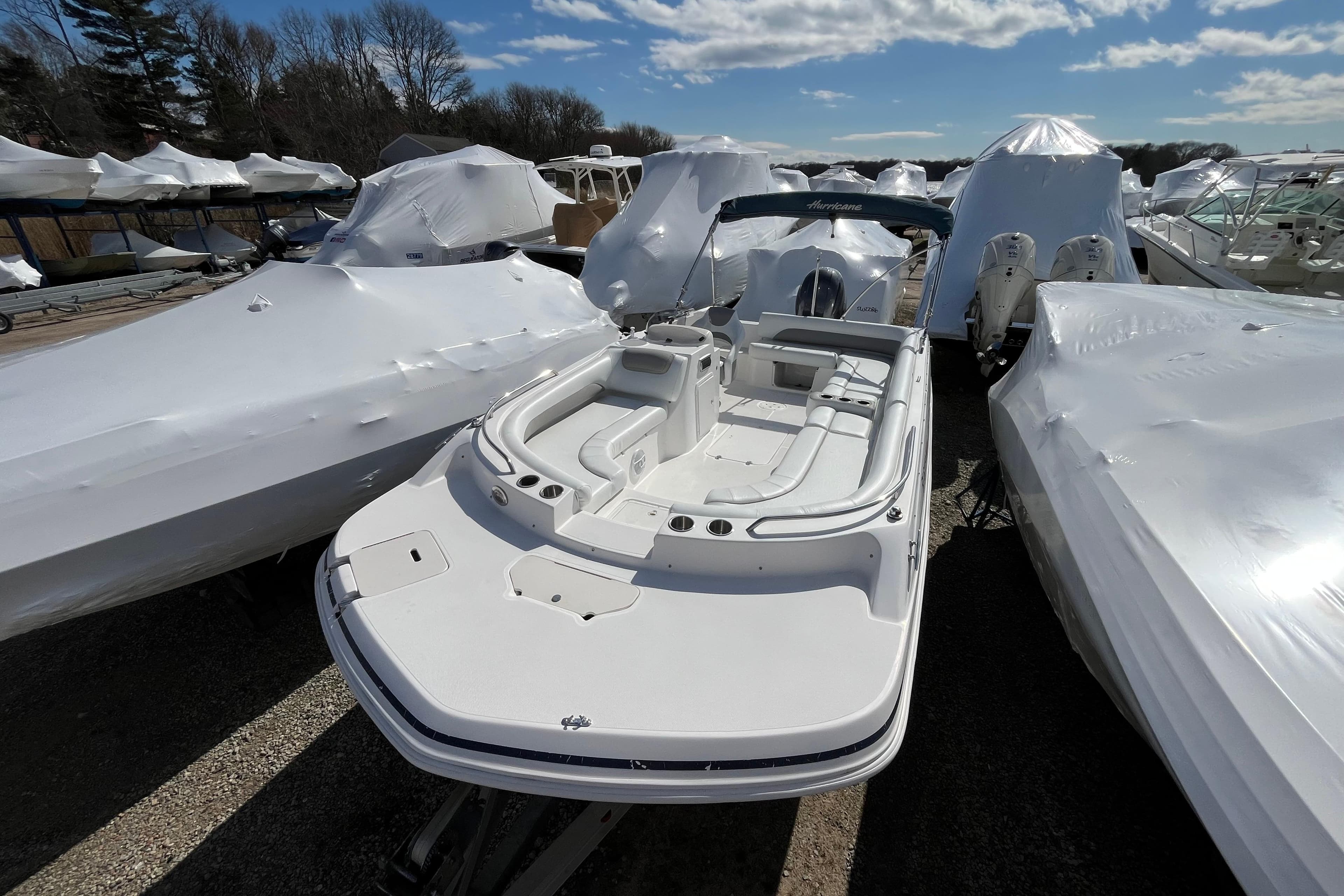 2015 Hurricane SunDeck Sport 201 OB boat in storage, surrounded by covered boats.