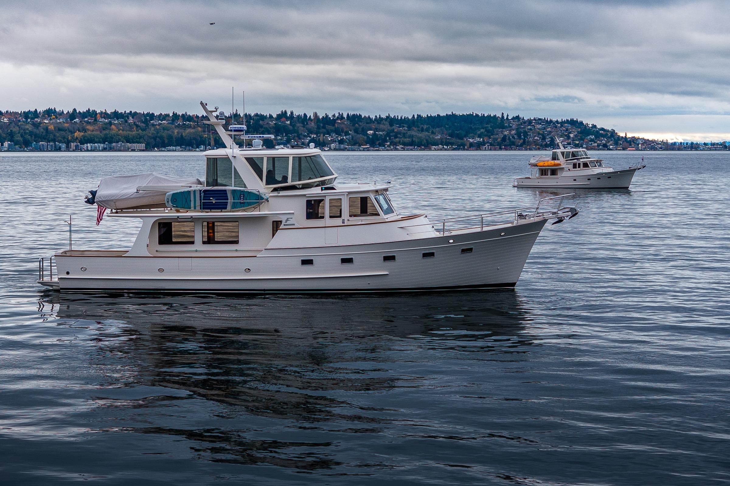 2026 Fleming 55 Pilothouse yacht on calm water under cloudy sky.
