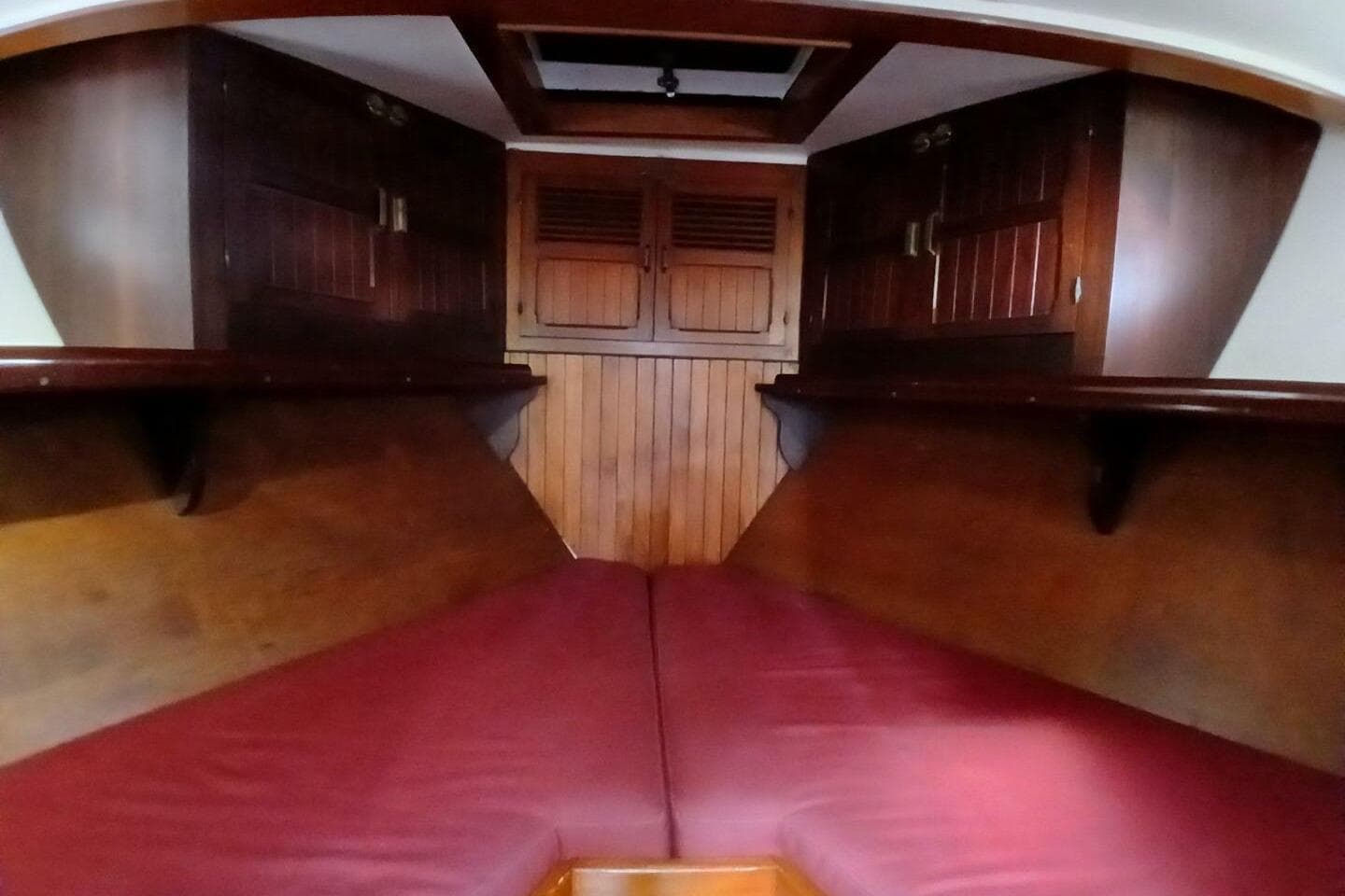 Interior cabin of 1980 Hardin 45 sailboat with wooden finish and red cushions.
