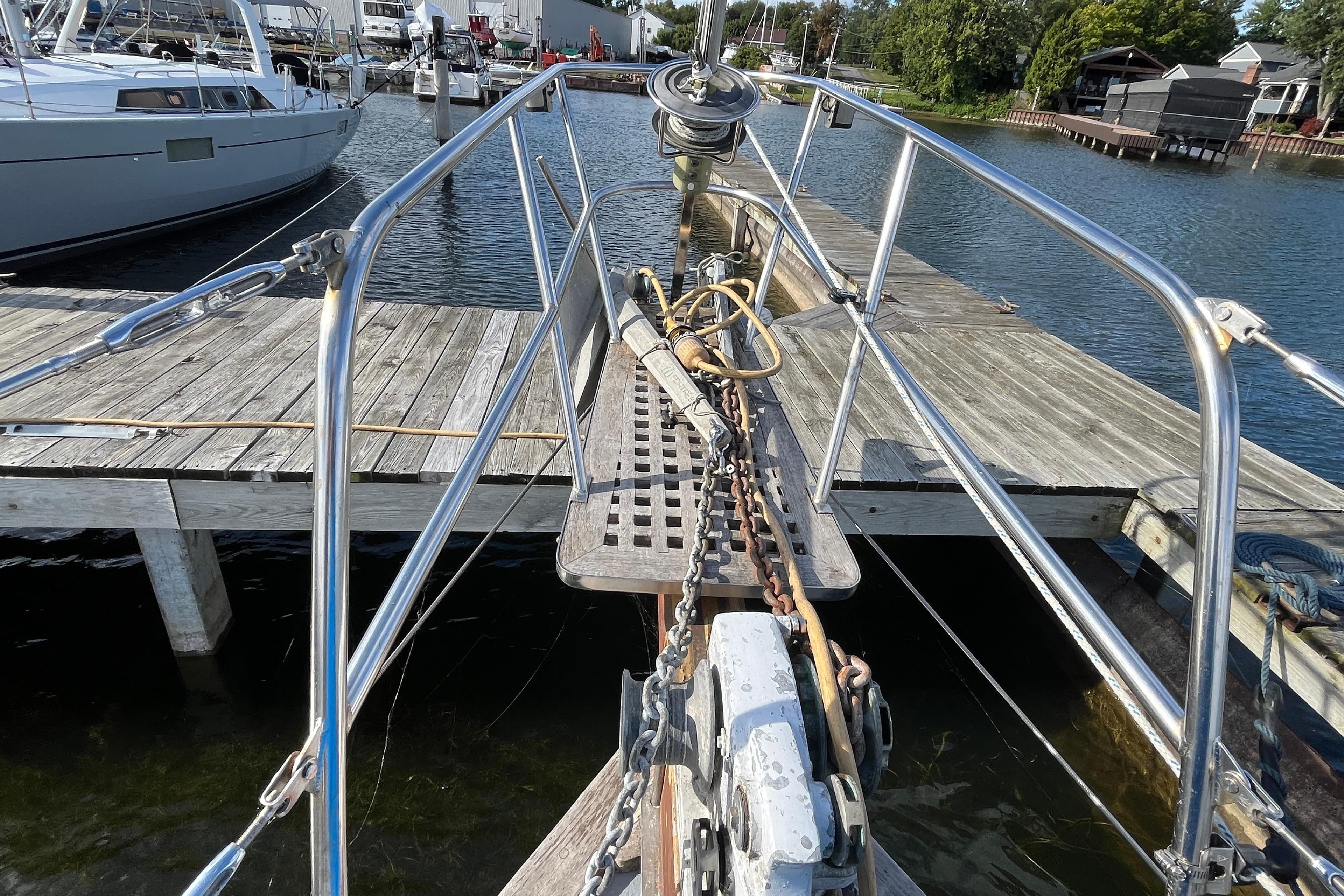 Bow of 1982 Tayana 37 sailboat docked at marina, featuring anchor and railing.