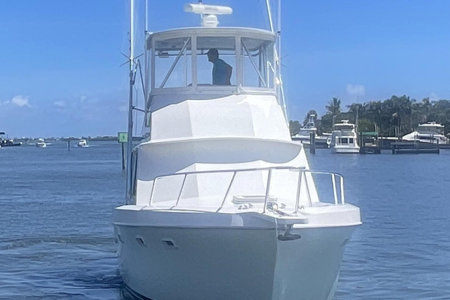1968 Hatteras 34 Sport Fisherman boat cruising on a sunny day near a marina.