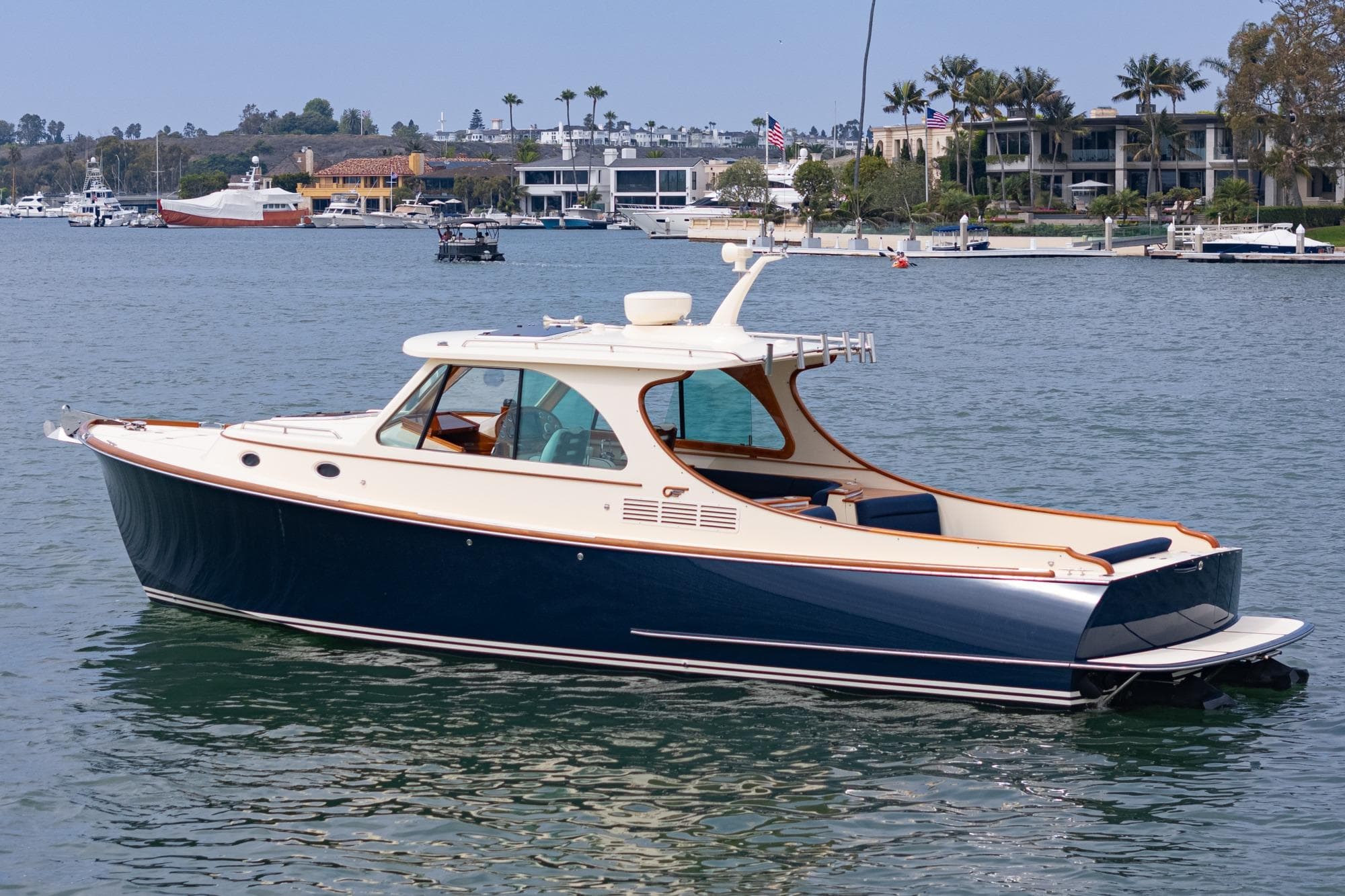 2014 Hinckley Talaria 34 yacht on calm waters near luxury waterfront homes.