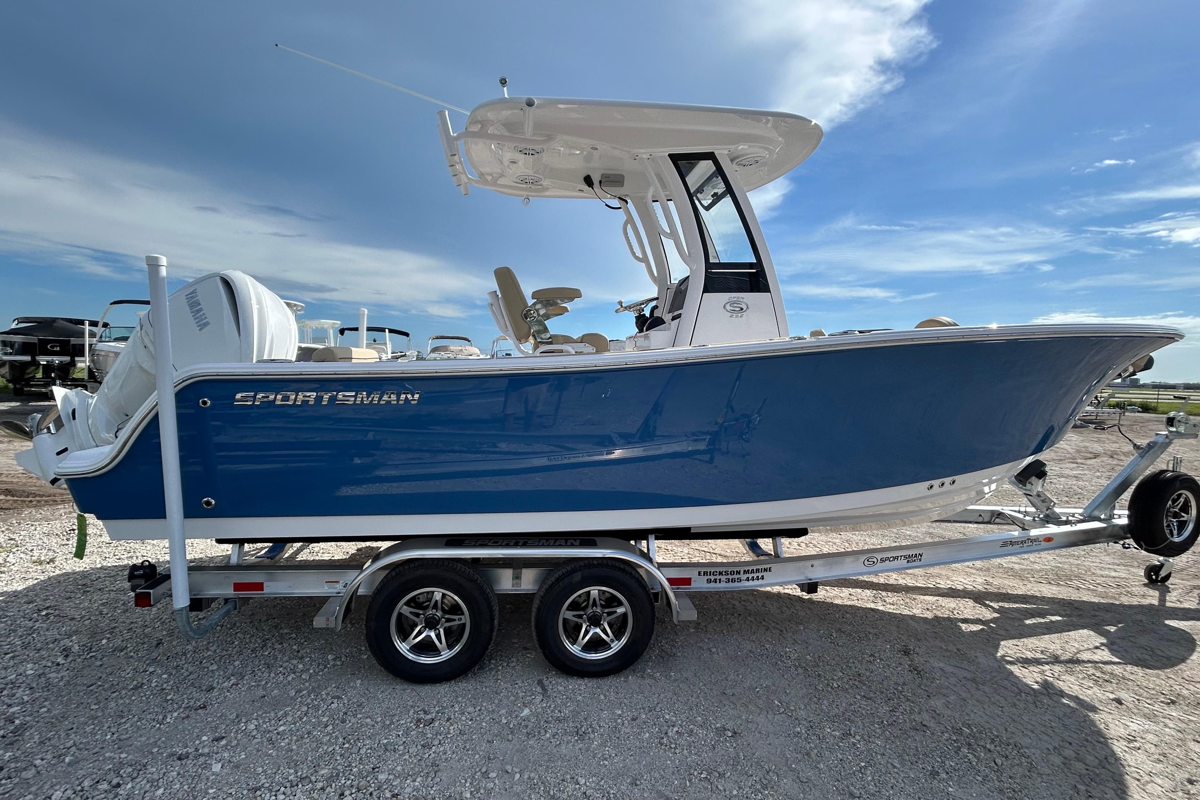 2026 Sportsman Open 232 Center Console boat on trailer, blue hull, sunny day.