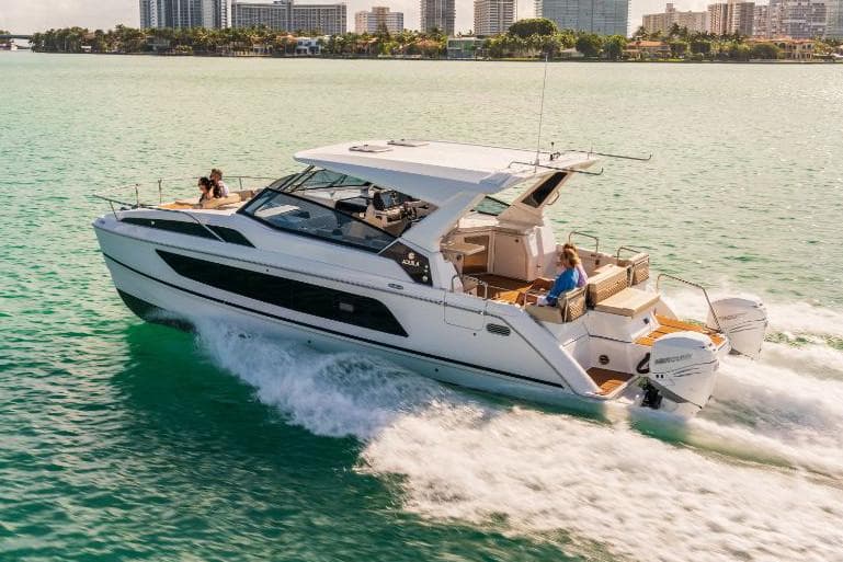 Manufacturer Provided Image: 2021 Aquila 36 Sport cruising on turquoise water near city skyline.