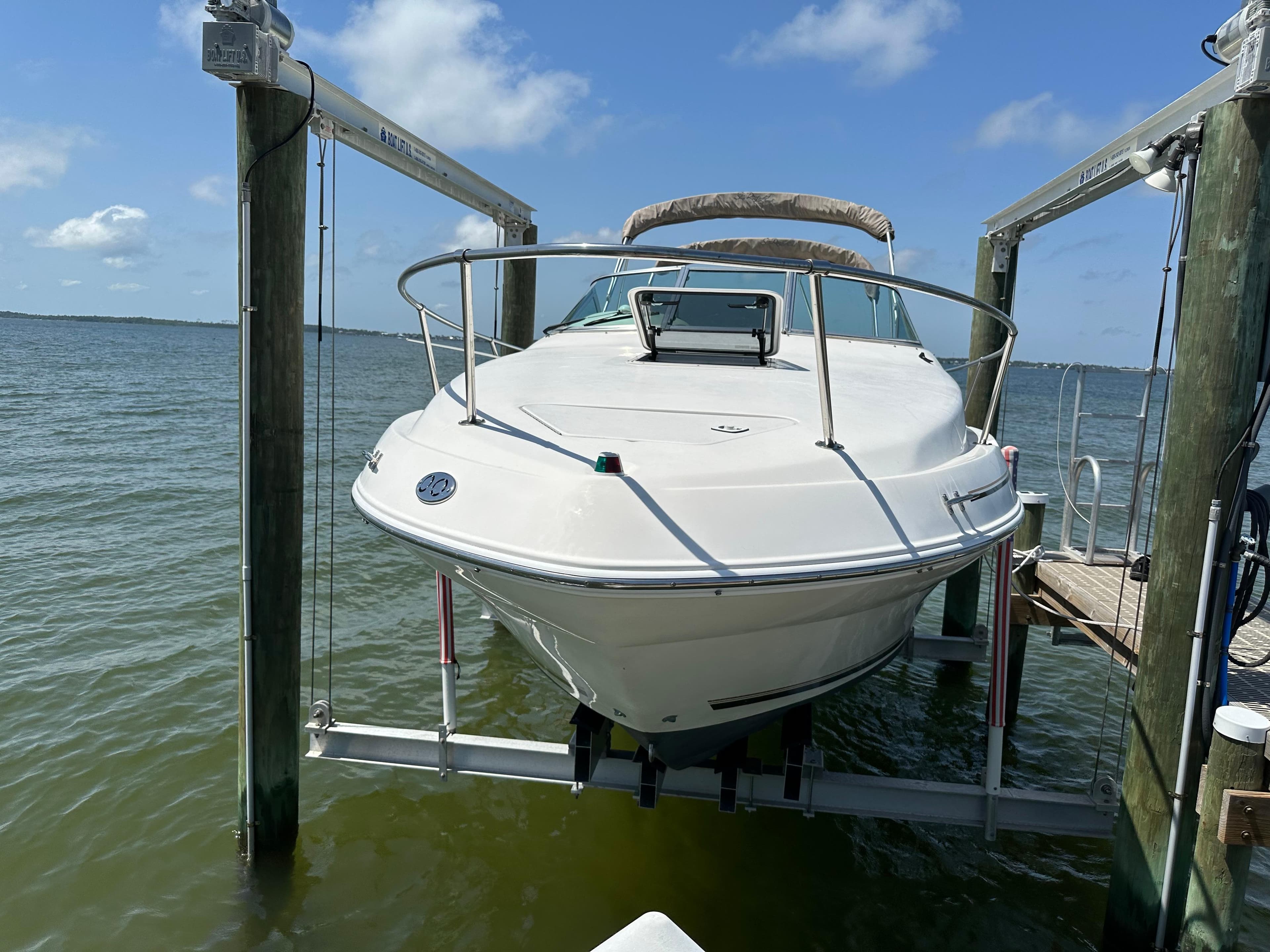 1998 Sea Ray 240 Sundancer boat on lift, docked by the water.