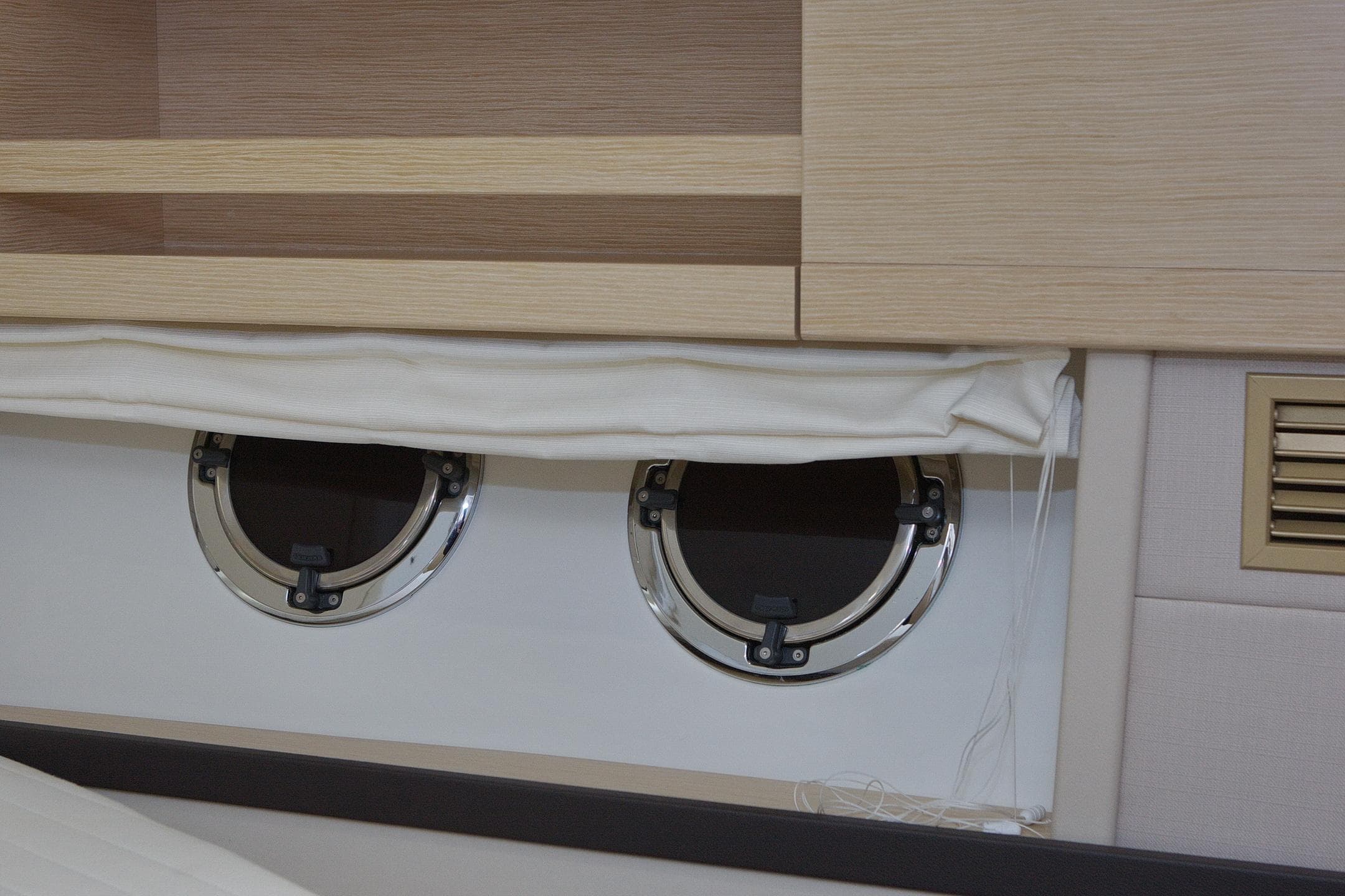 Interior of 2014 Greenline 48 Fly yacht with round portholes and wooden cabinetry.