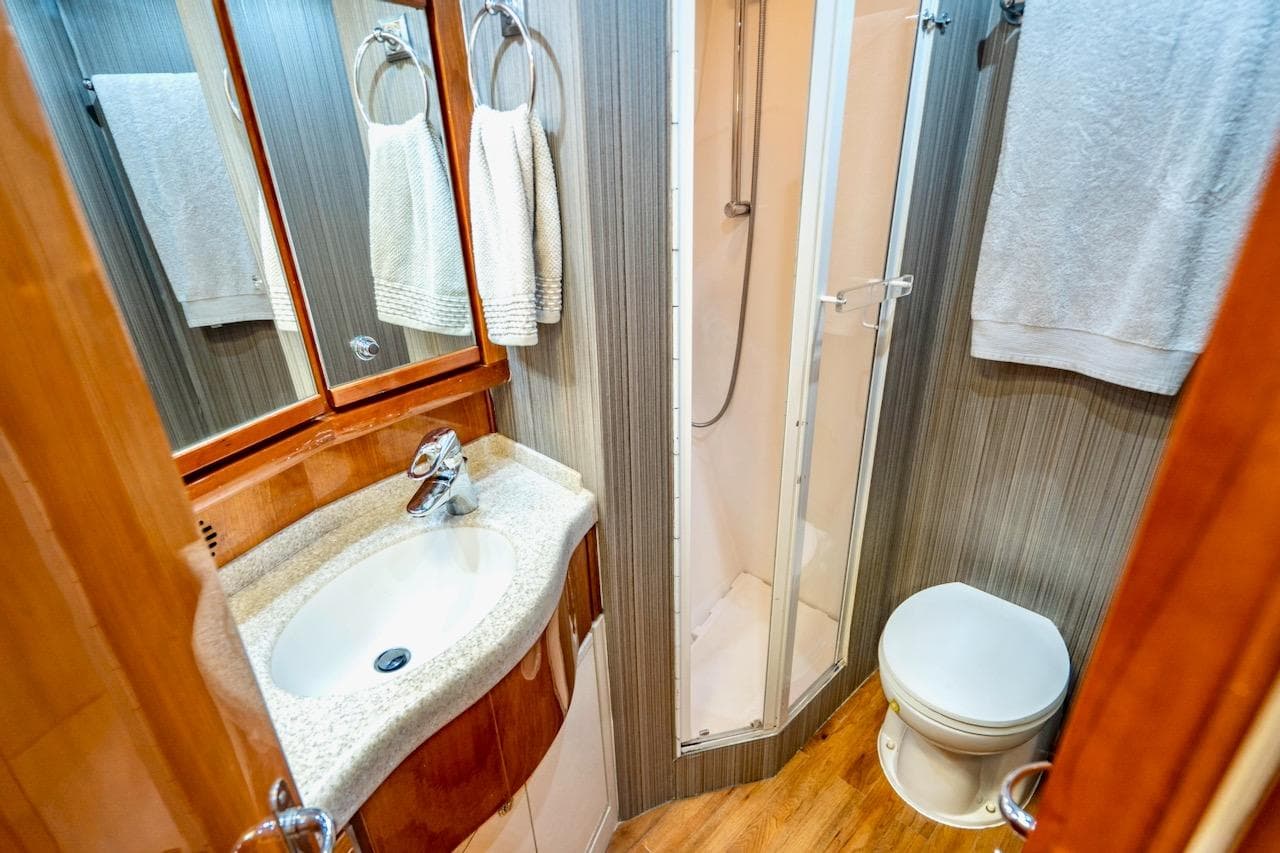 Luxurious bathroom in 2001 Bertram 510 Convertible yacht with shower, sink, and toilet.