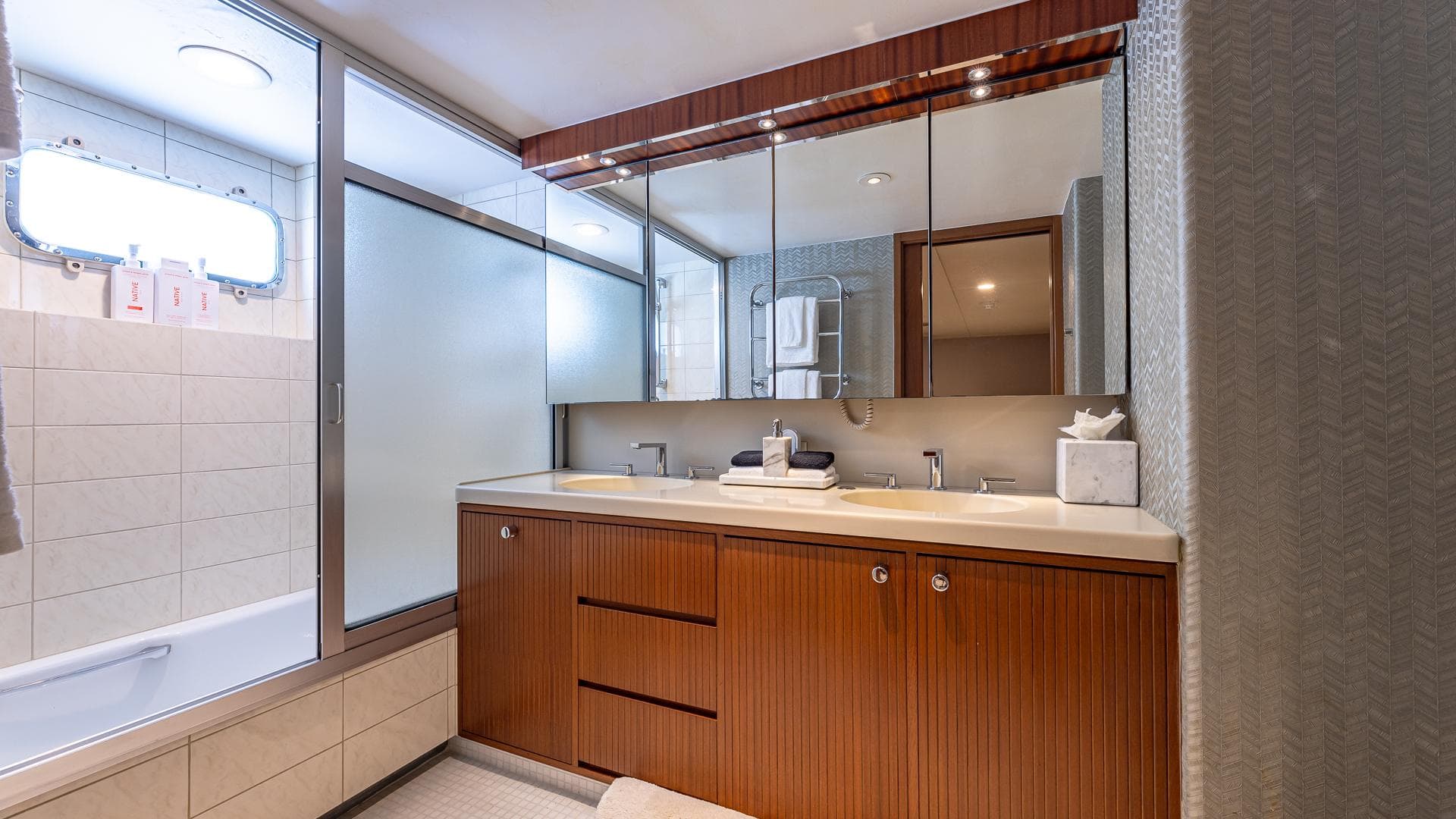 Luxurious bathroom on 1985 Feadship Custom yacht, featuring wood cabinetry and modern fixtures.
