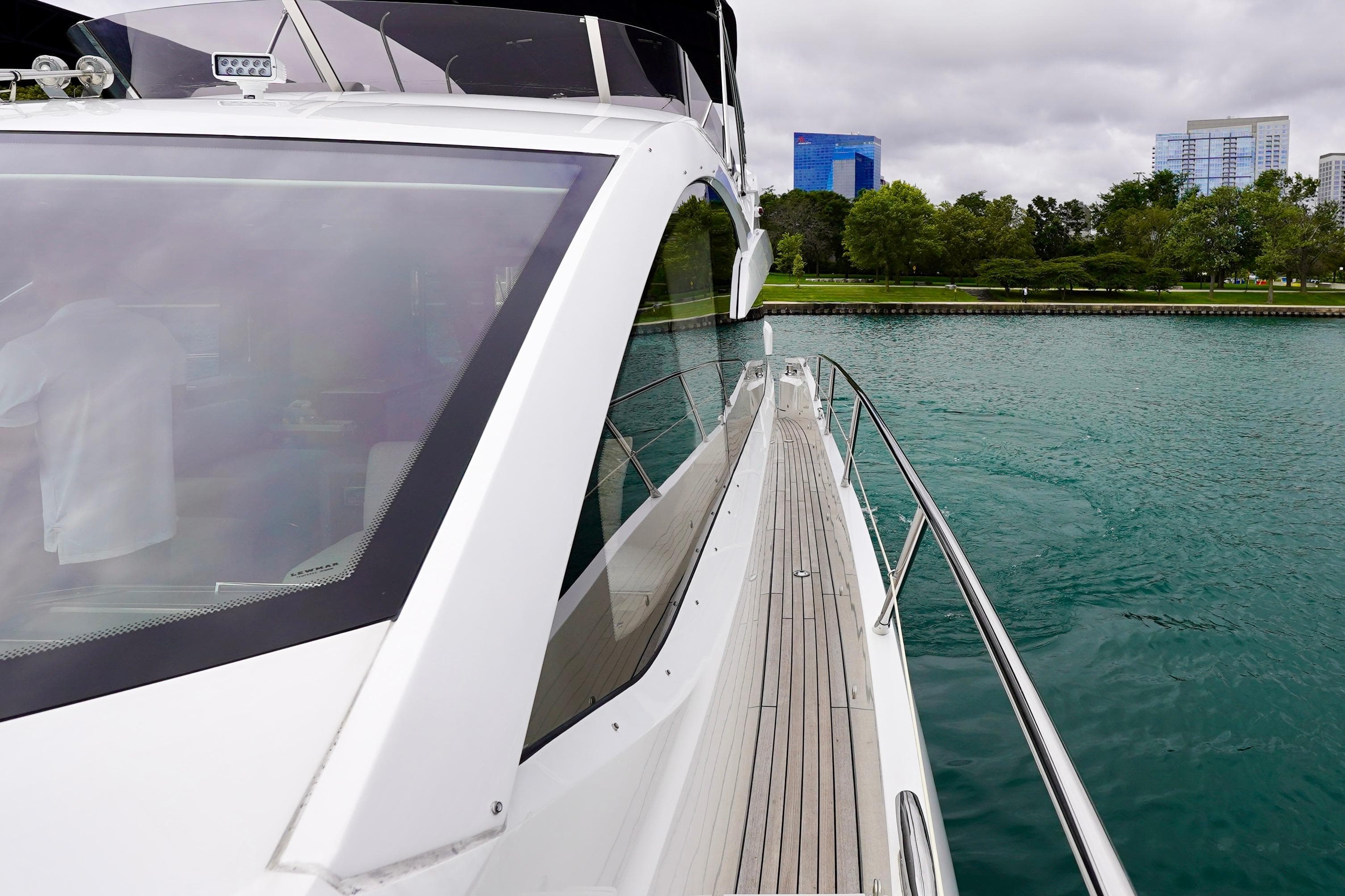 2019 Sunseeker Manhattan 66 yacht on calm water near a cityscape.