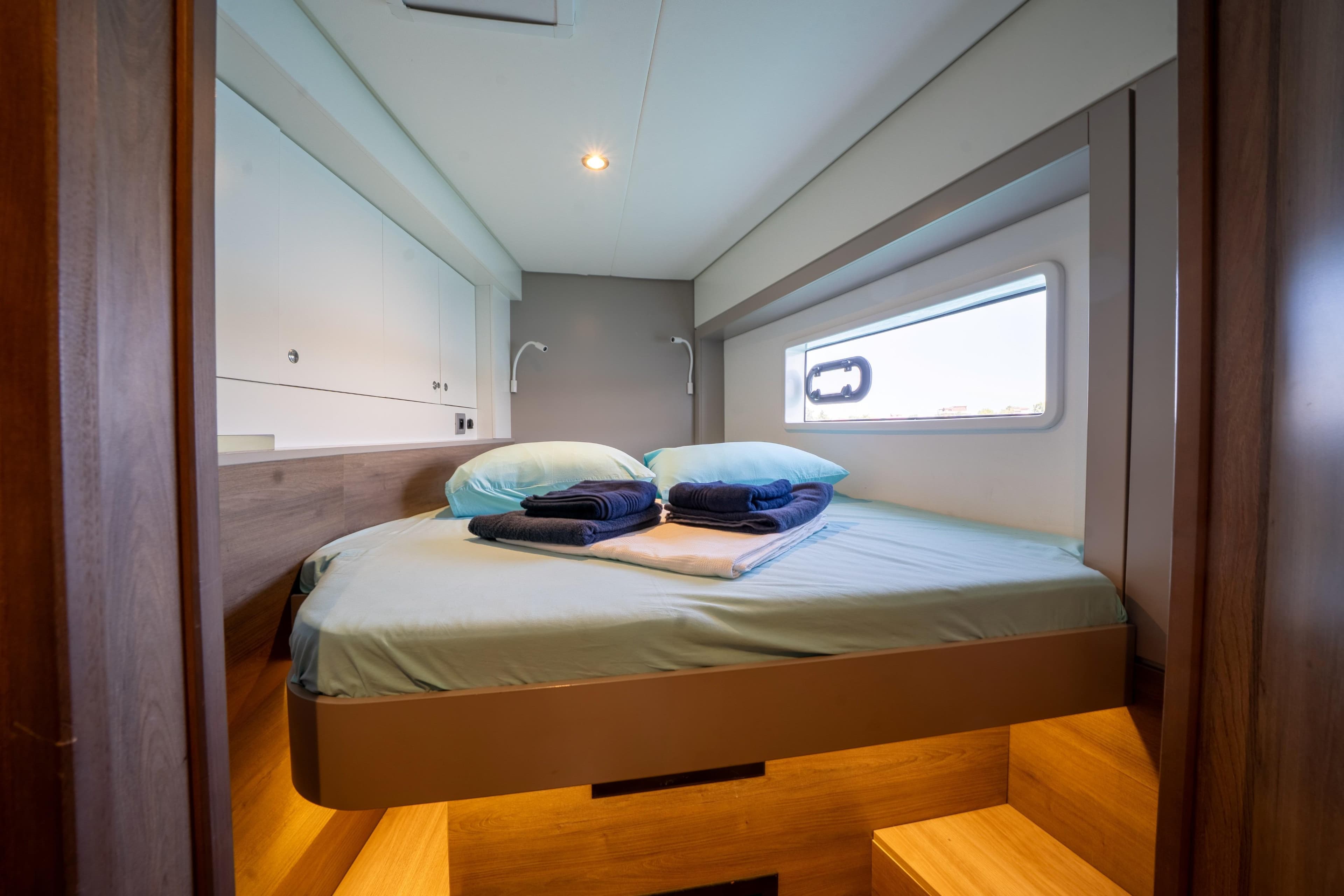 Luxurious cabin interior of 2022 Bali 4.2 yacht with cozy bed and window view.