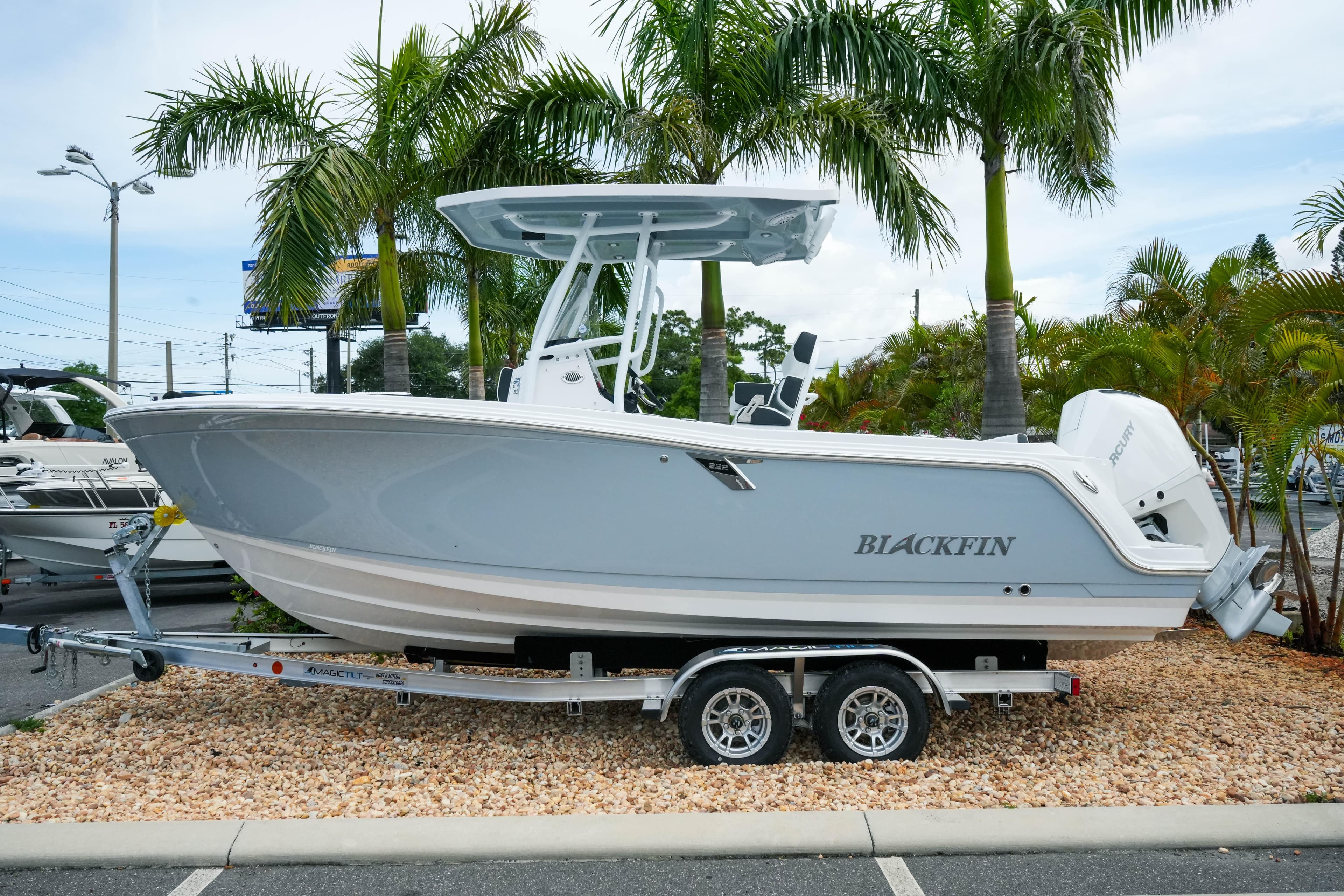 2026 Blackfin 222 CC boat on trailer, surrounded by palm trees.