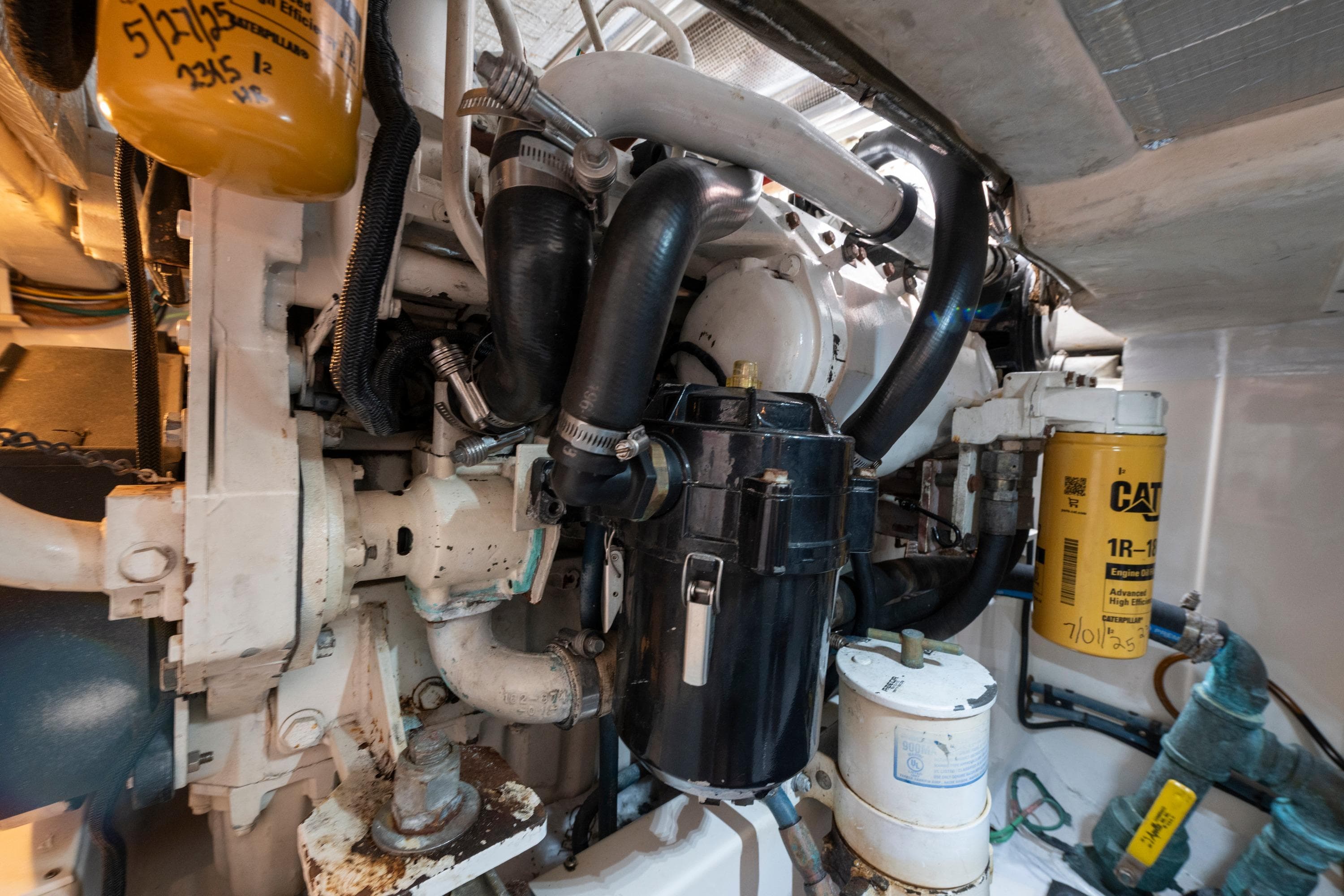 Engine room of a 2005 Cabo 35 Flybridge boat, showcasing mechanical components and filters.