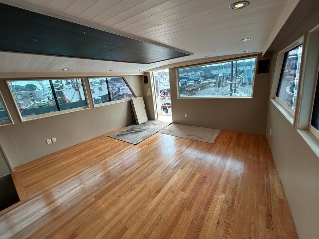 Spacious interior of 1991 Hatteras Cockpit Motor Yacht with wooden flooring and large windows.