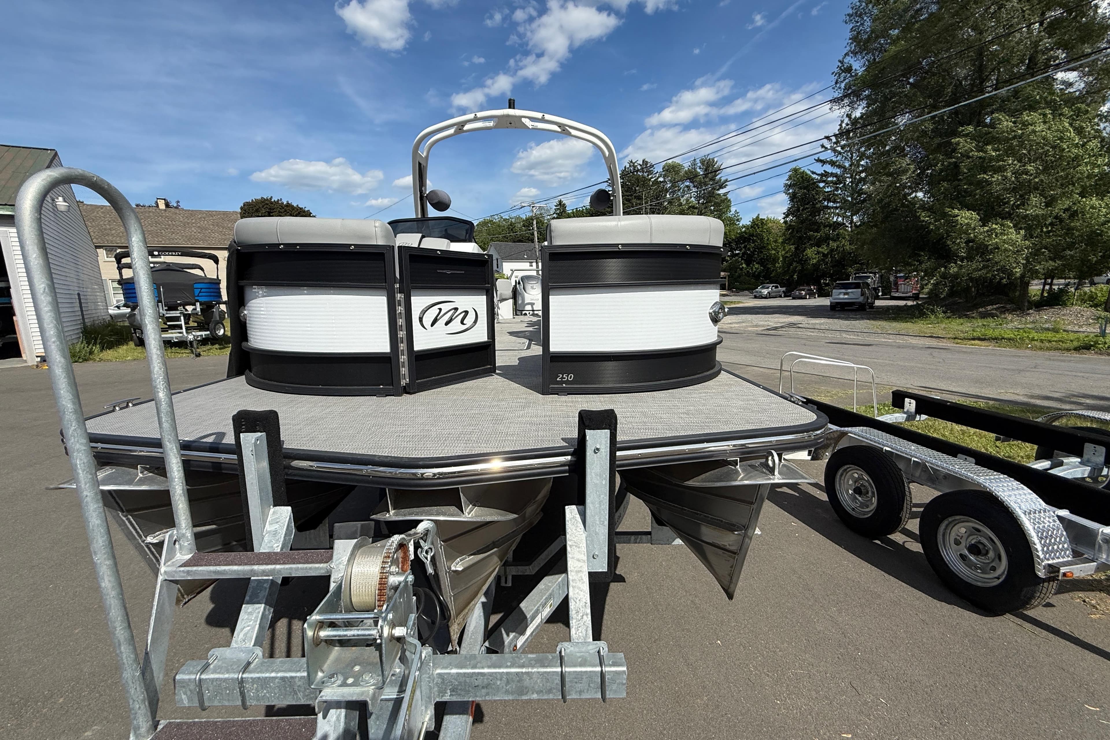 2023 Manitou 25 LX RFXW pontoon boat on trailer under a clear blue sky.