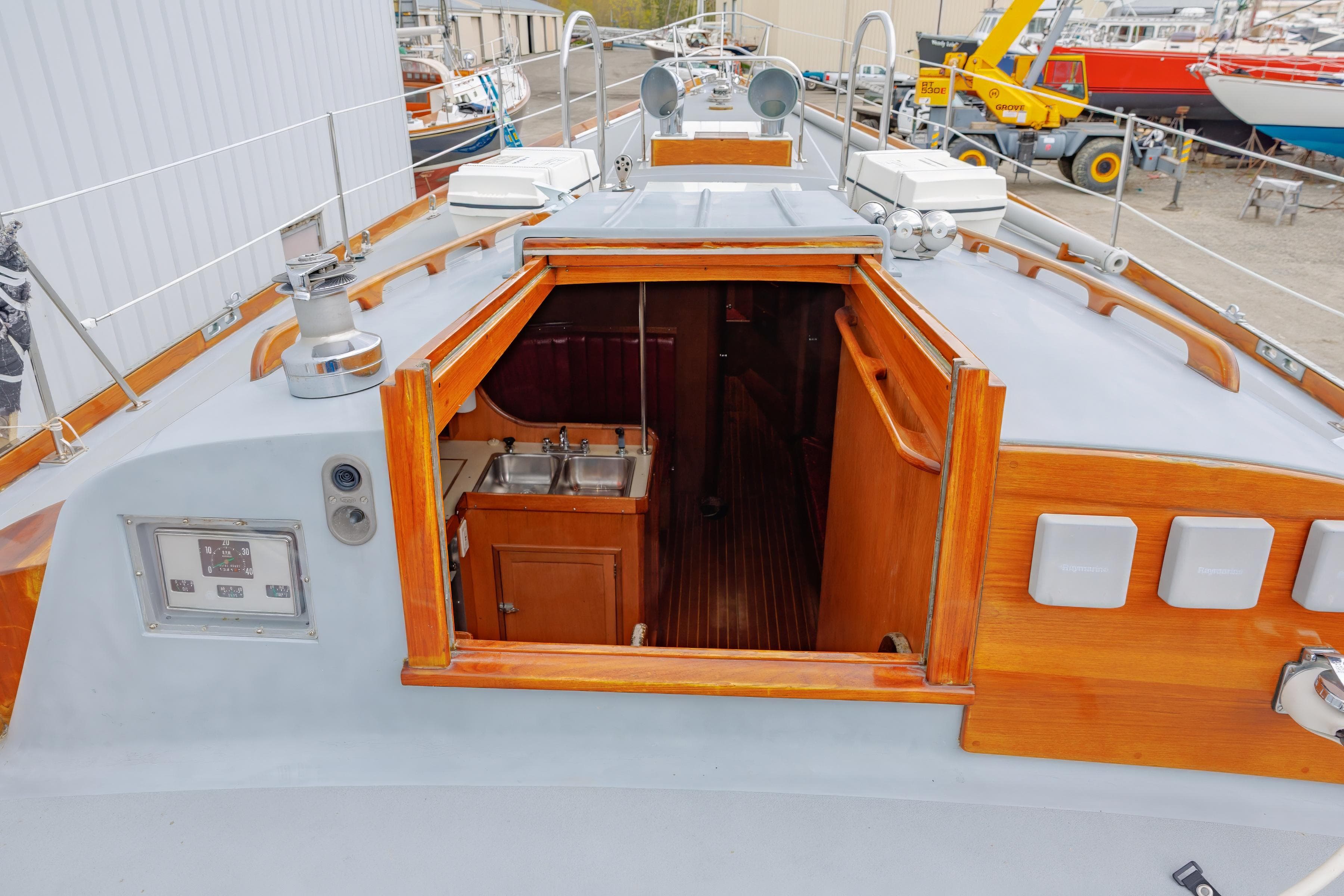 Hinckley 48 sailboat interior view, showcasing wooden cabinetry and dual sinks, docked in a marina.