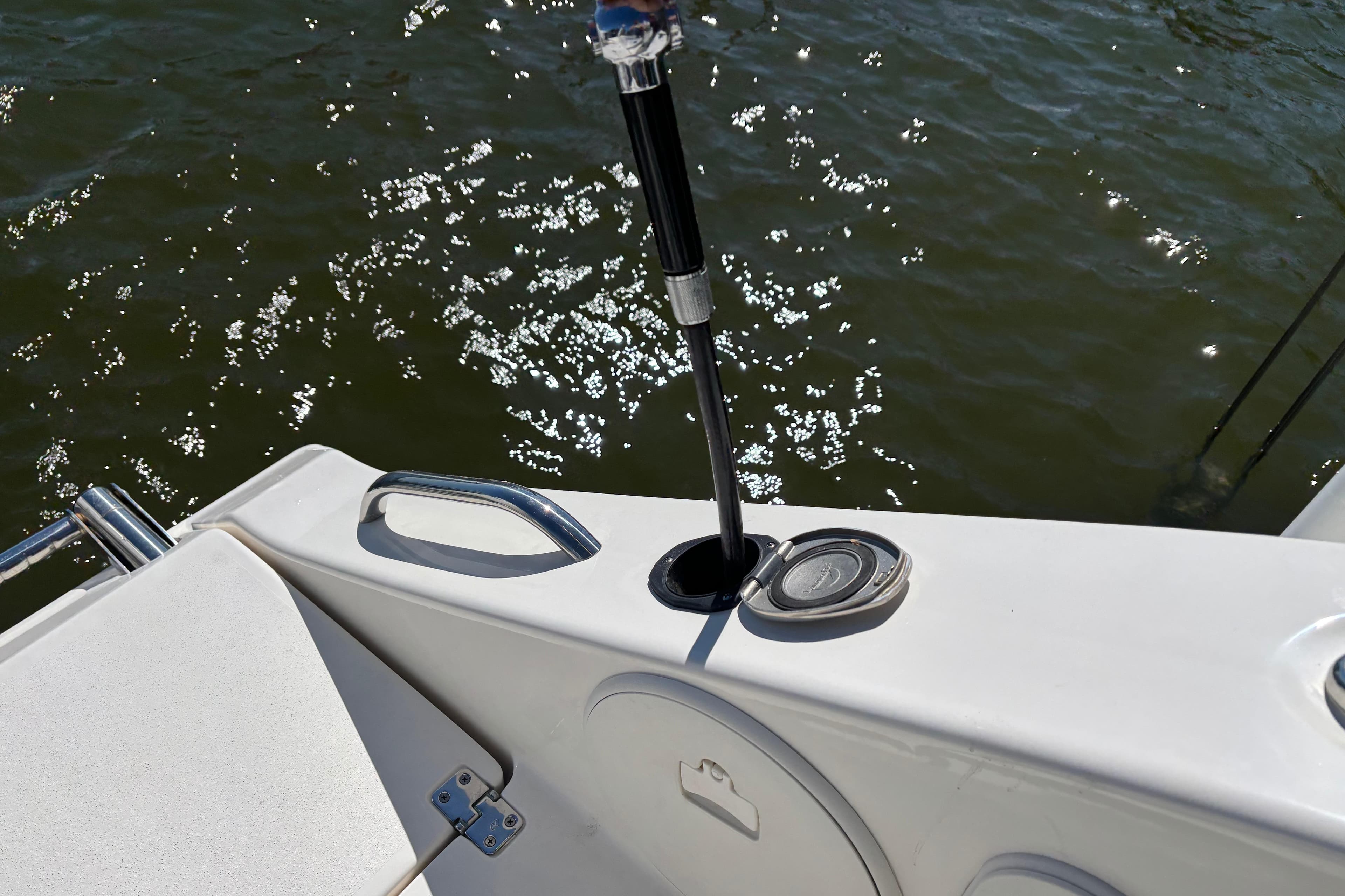 2023 Cobia 301 Center Console boat detail with rod holder and water reflections.