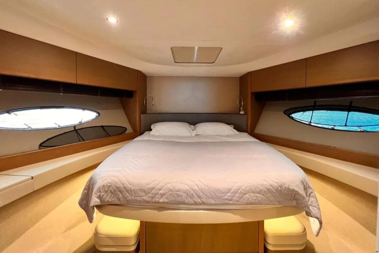 Luxurious bedroom interior of 2014 Princess 52 yacht with elegant wood finish and porthole windows.