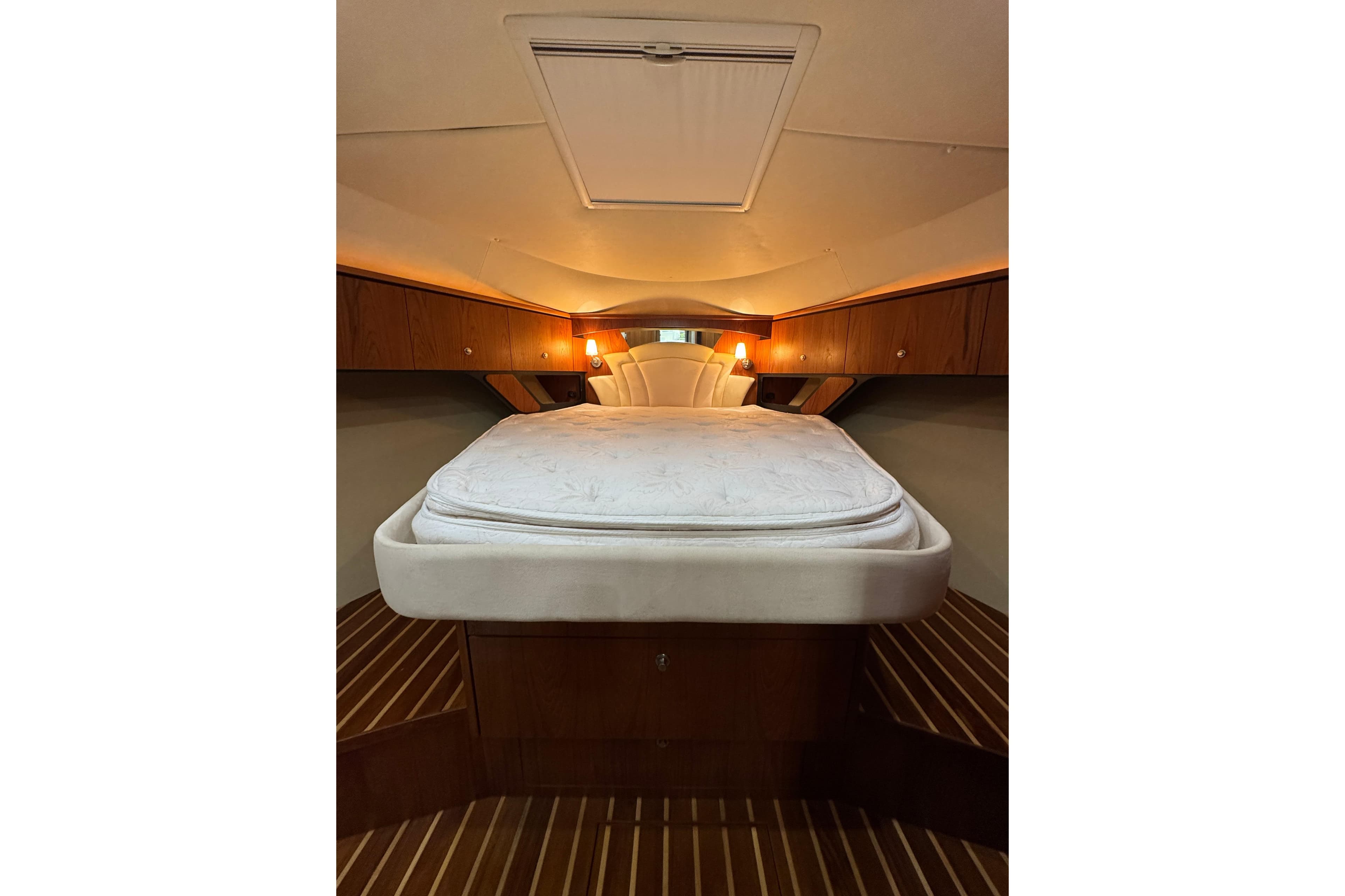 Luxurious cabin interior of 2007 Tiara 43 yacht with cozy bed and wooden accents.