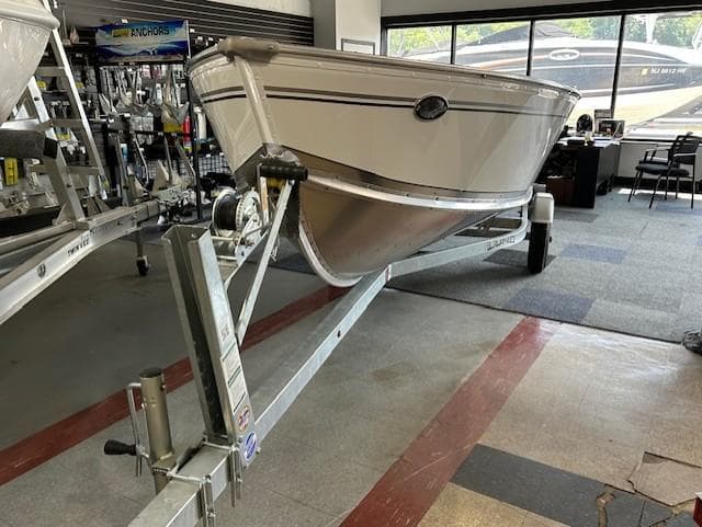 2026 Lund 1600 Fury Tiller boat on trailer in showroom.