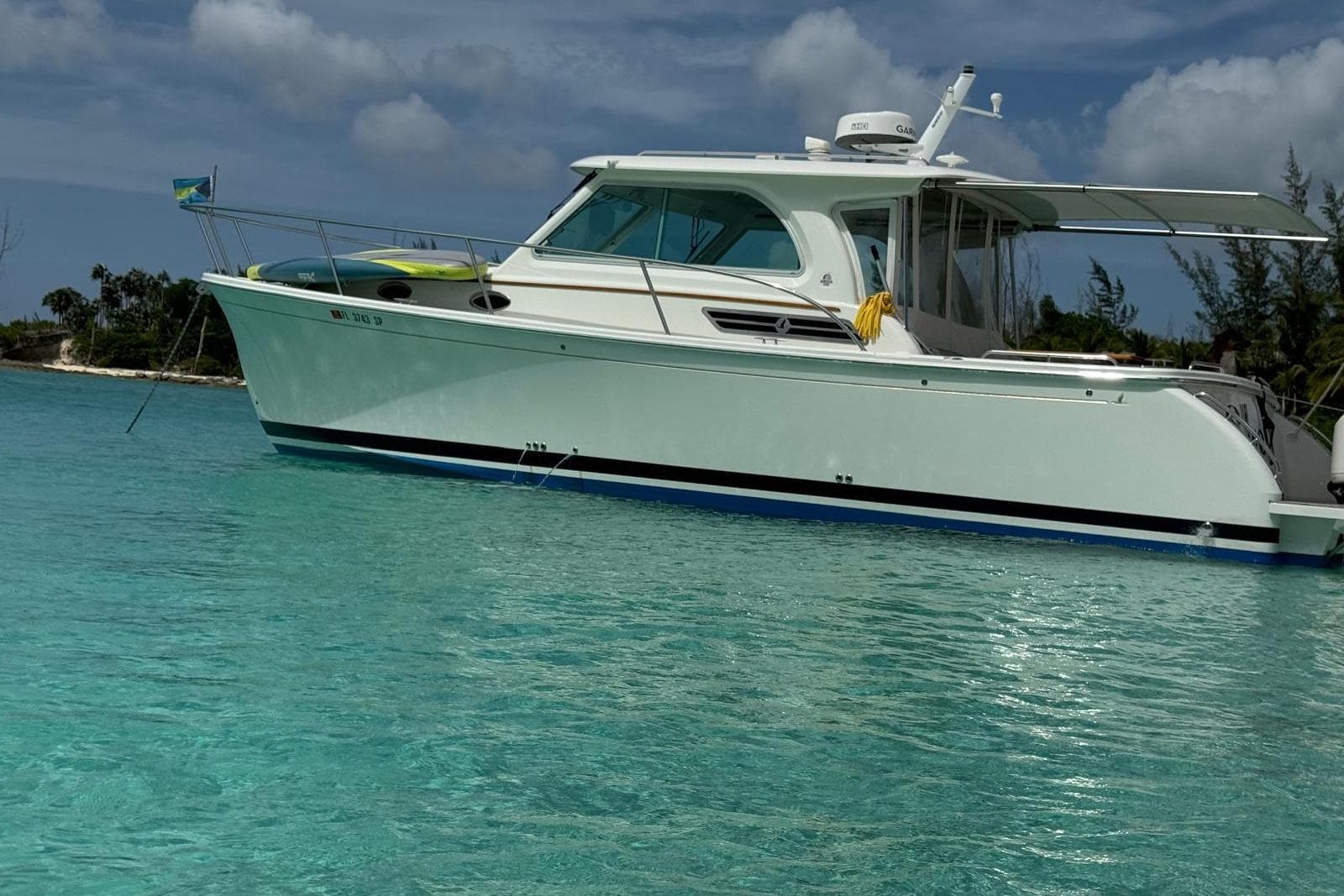 2020 Back Cove 34O boat anchored in clear turquoise water, under a partly cloudy sky.