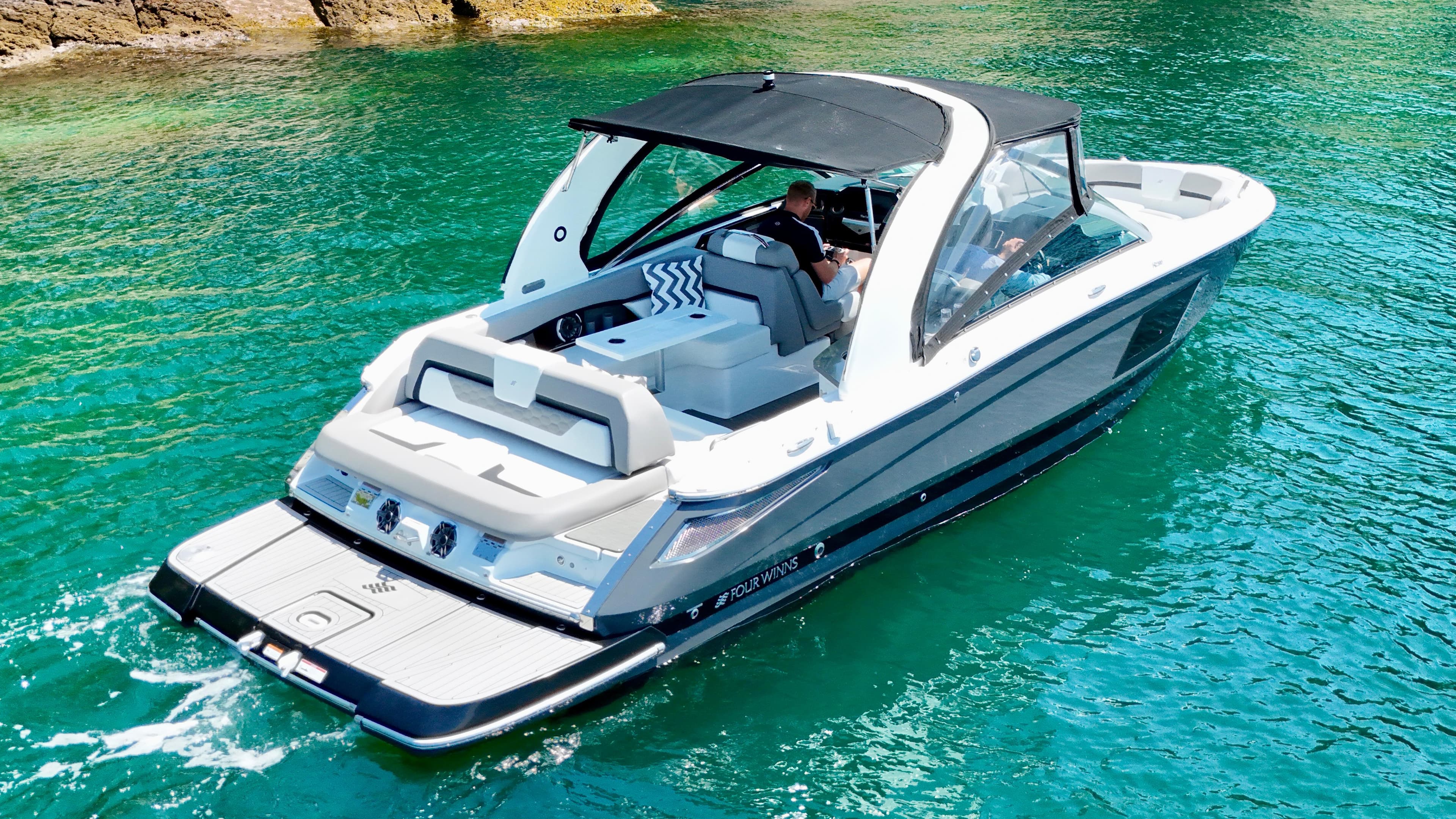 2023 Four Winns H290 boat cruising on clear turquoise water.