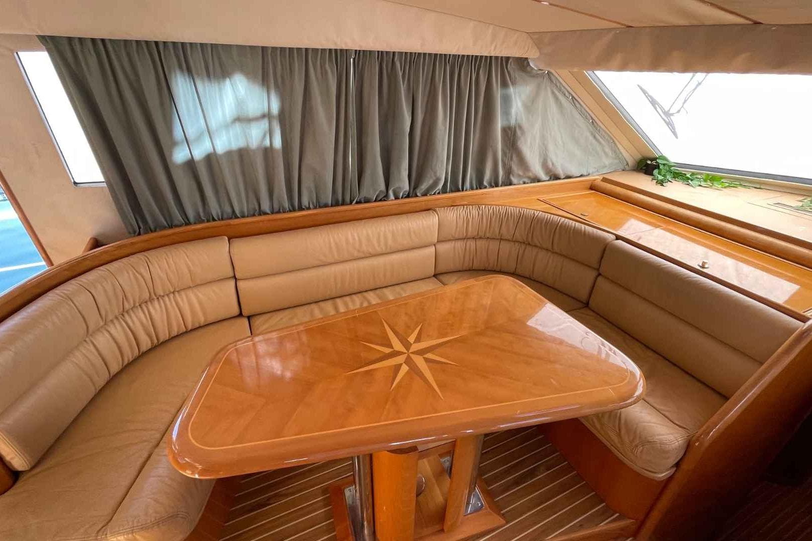 Luxurious interior of 1998 Guy Couach 2100 yacht with elegant wood table and leather seating.