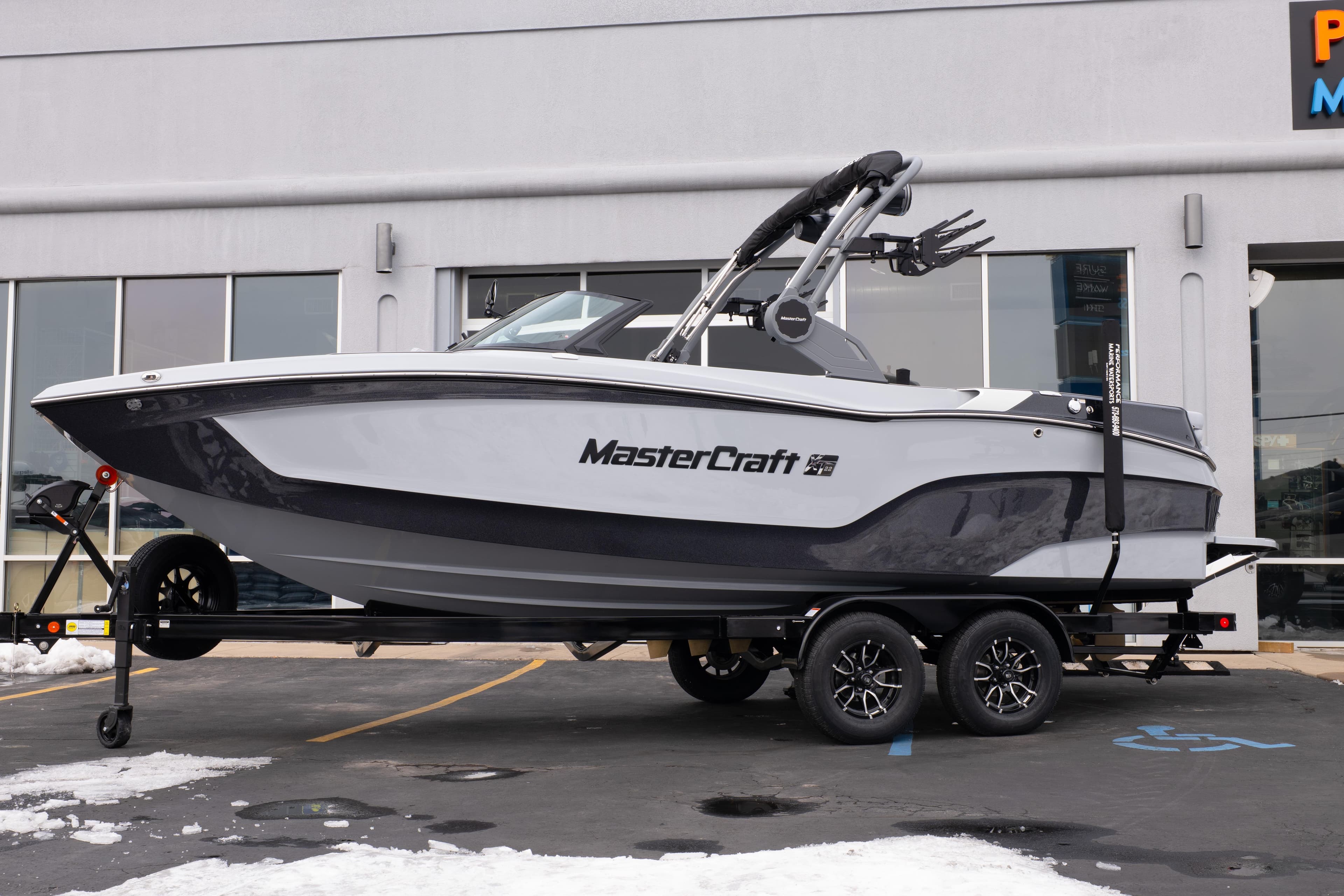 2026 MasterCraft XT22 boat on trailer, parked outside a building in snowy conditions.