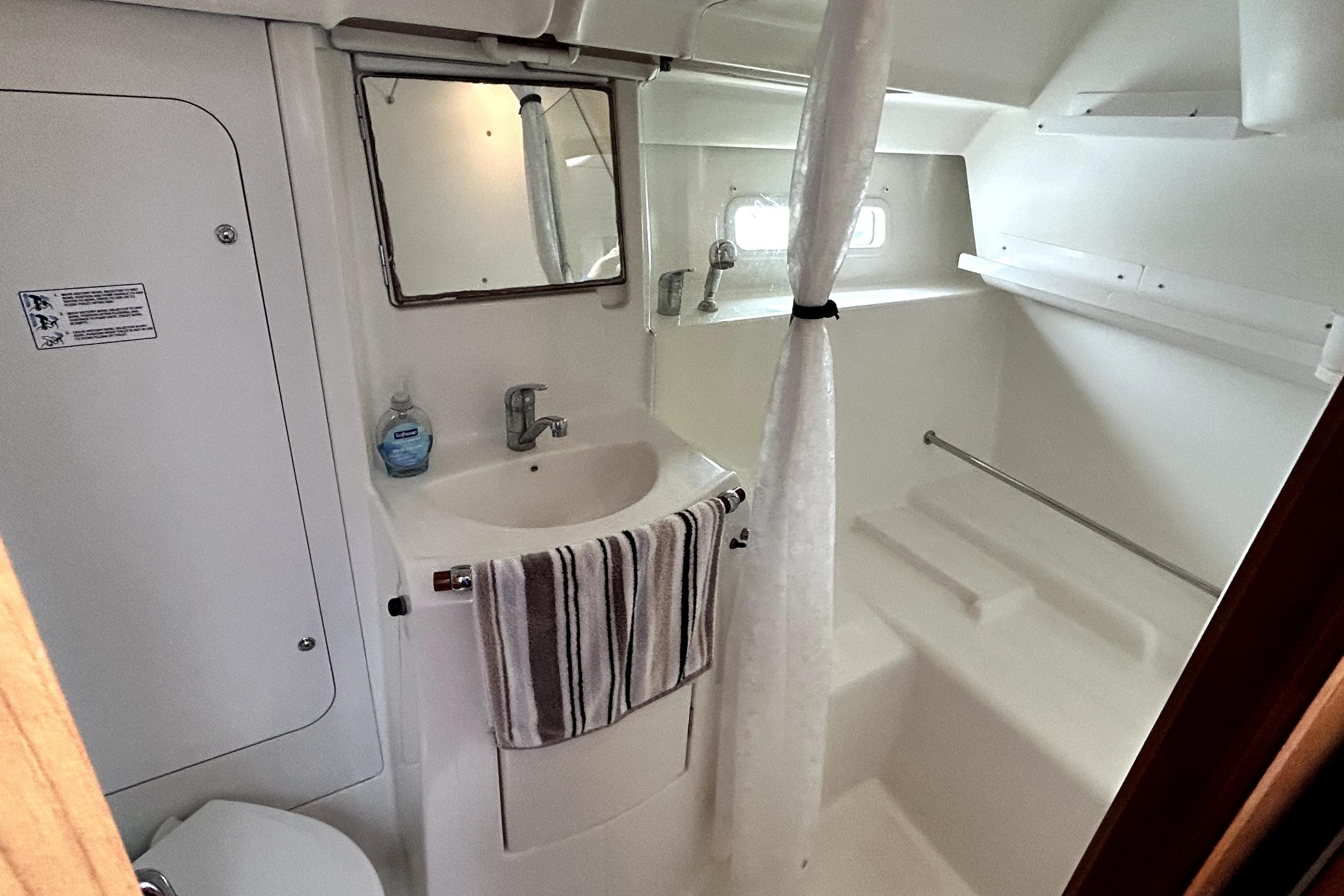 Bathroom interior of 2005 Beneteau Oceanis 373 yacht, featuring sink, mirror, and shower area.