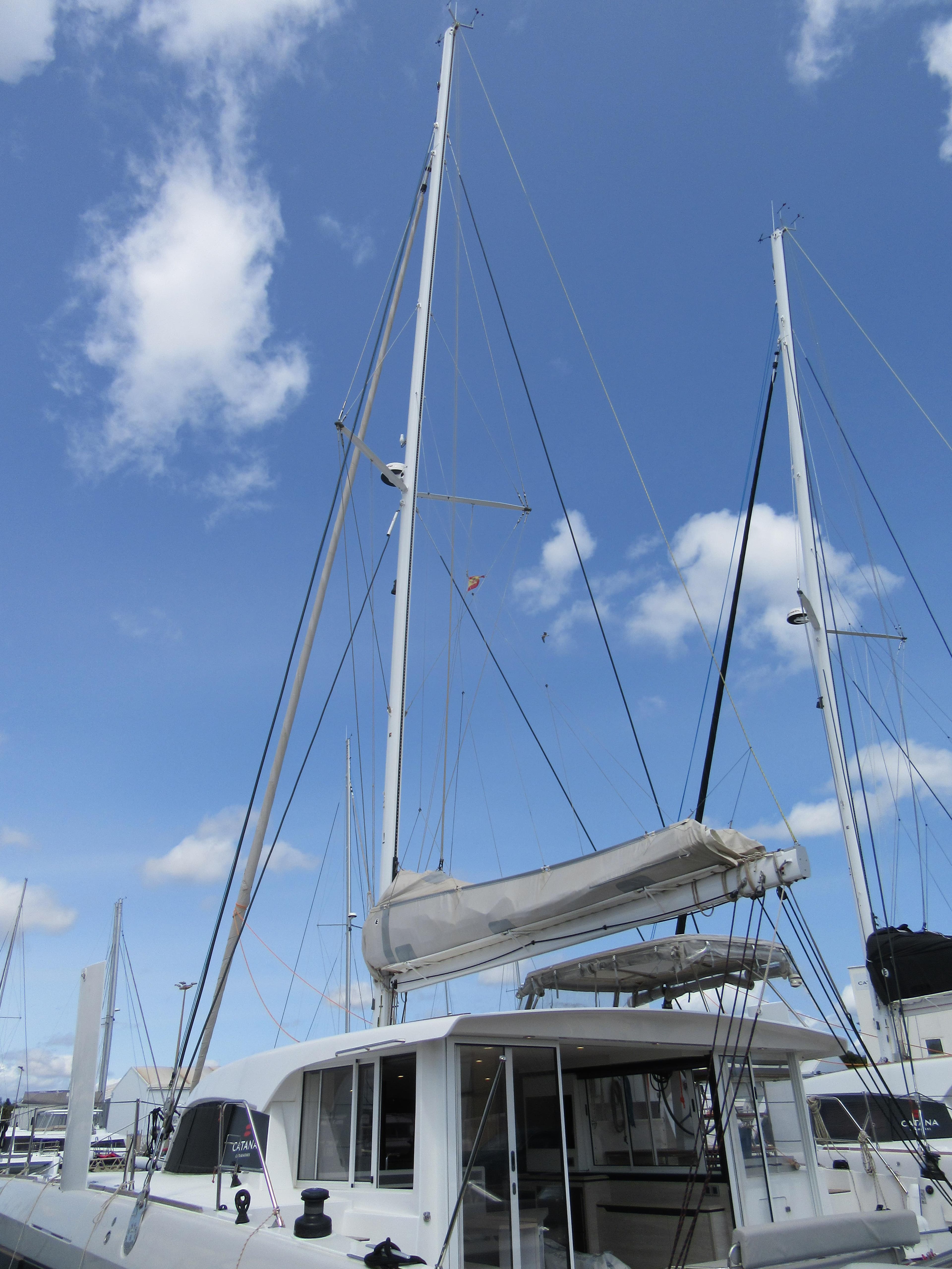 2023 Catana OC 50 catamaran with sails, docked under a clear blue sky.