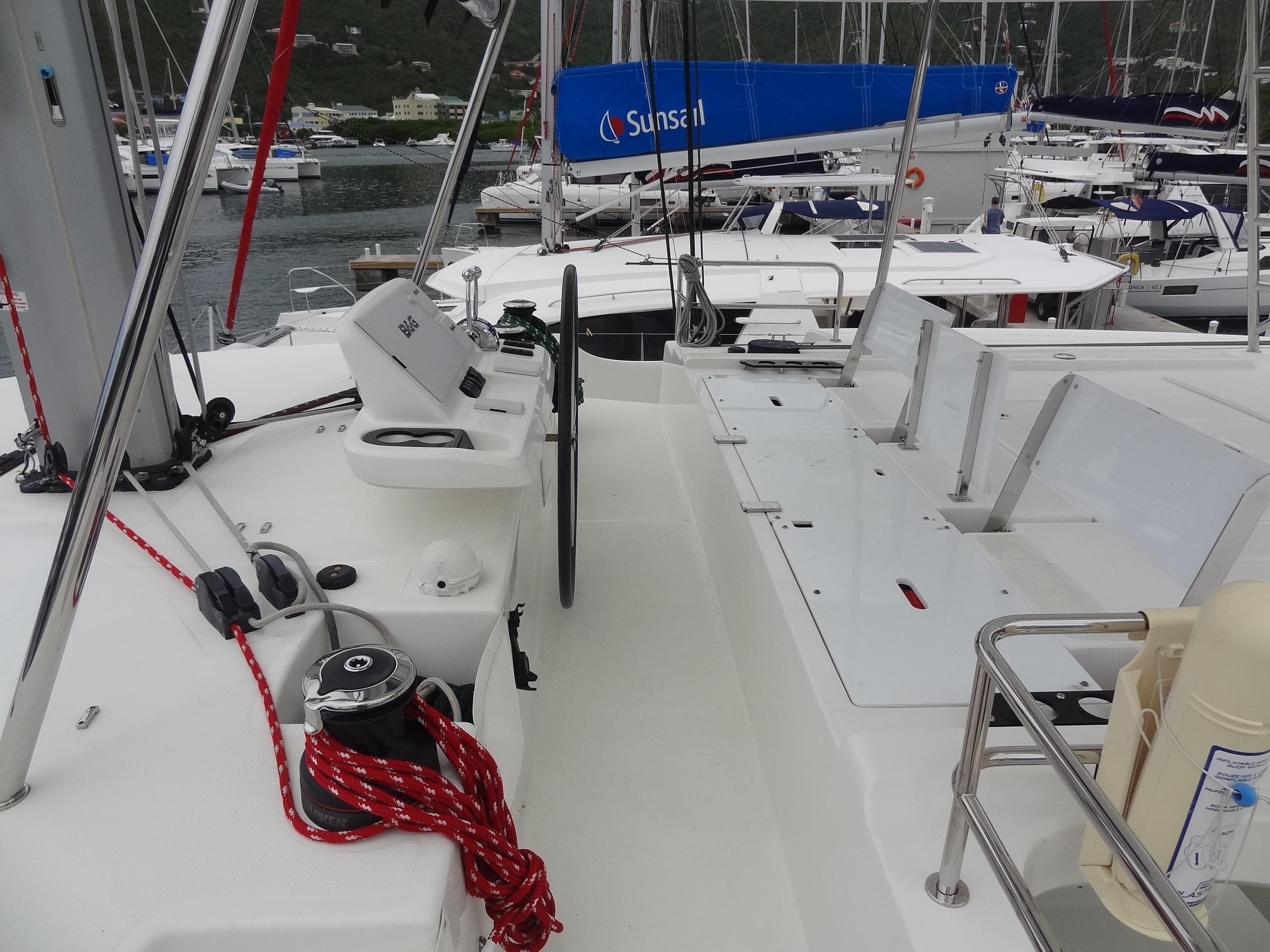2021 Lagoon 50 catamaran deck with steering wheel and ropes, docked at marina.