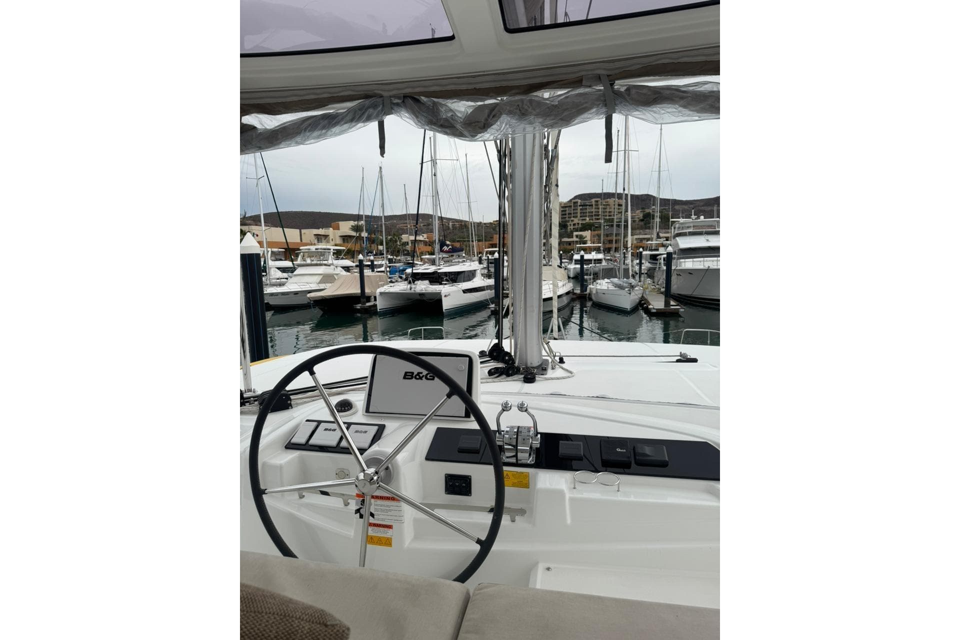 Helm of 2022 Lagoon 46 catamaran in marina, featuring B&G navigation system.